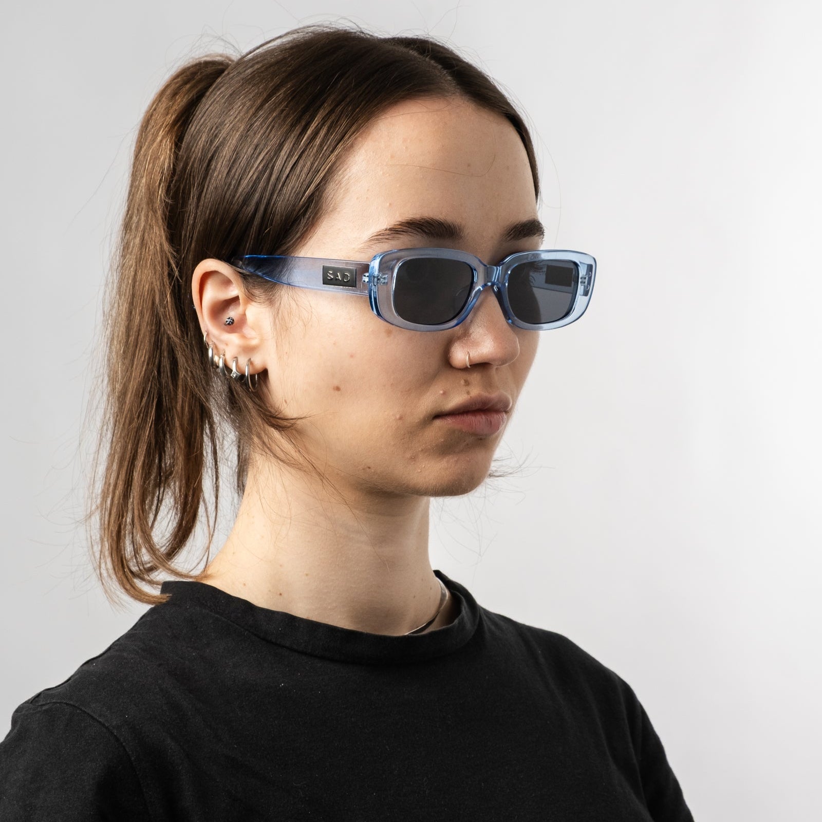 Female wearing Sad Eyewear Bouquet rectangle sunglasses in arctic blue with black tinted lenses