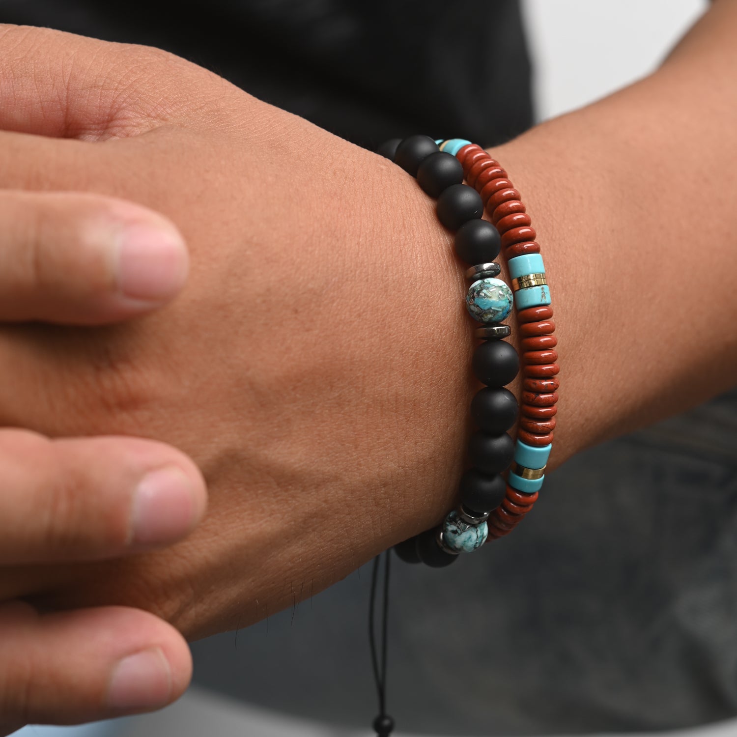 Photo of a man wearing two beaded bracelets, black beaded bracelets for men, ocean beaded bracelets for men