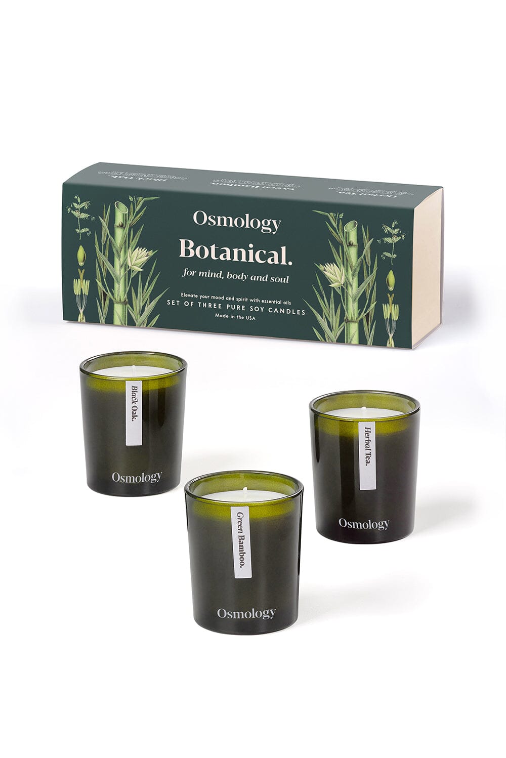 Osmology green botanical gift set of three miniature candles displayed next to product packaging against an orange-cream background