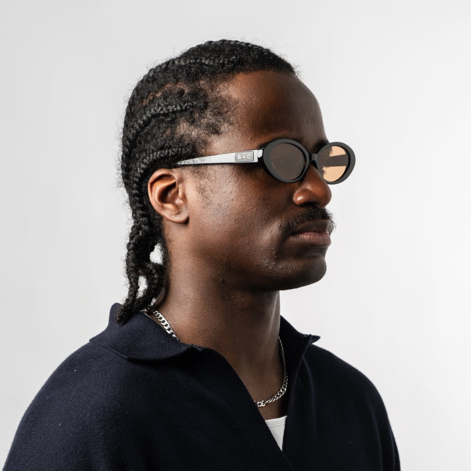 Male wearing Sad Eyewear Bloom oval sunglasses in black with tinted bronze lenses