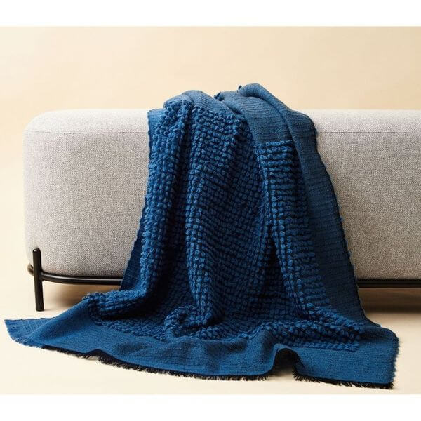 Macaroon Midnight Dark Blue Textured Merino Handloom Throw draped over a modern sofa in a cozy setting.