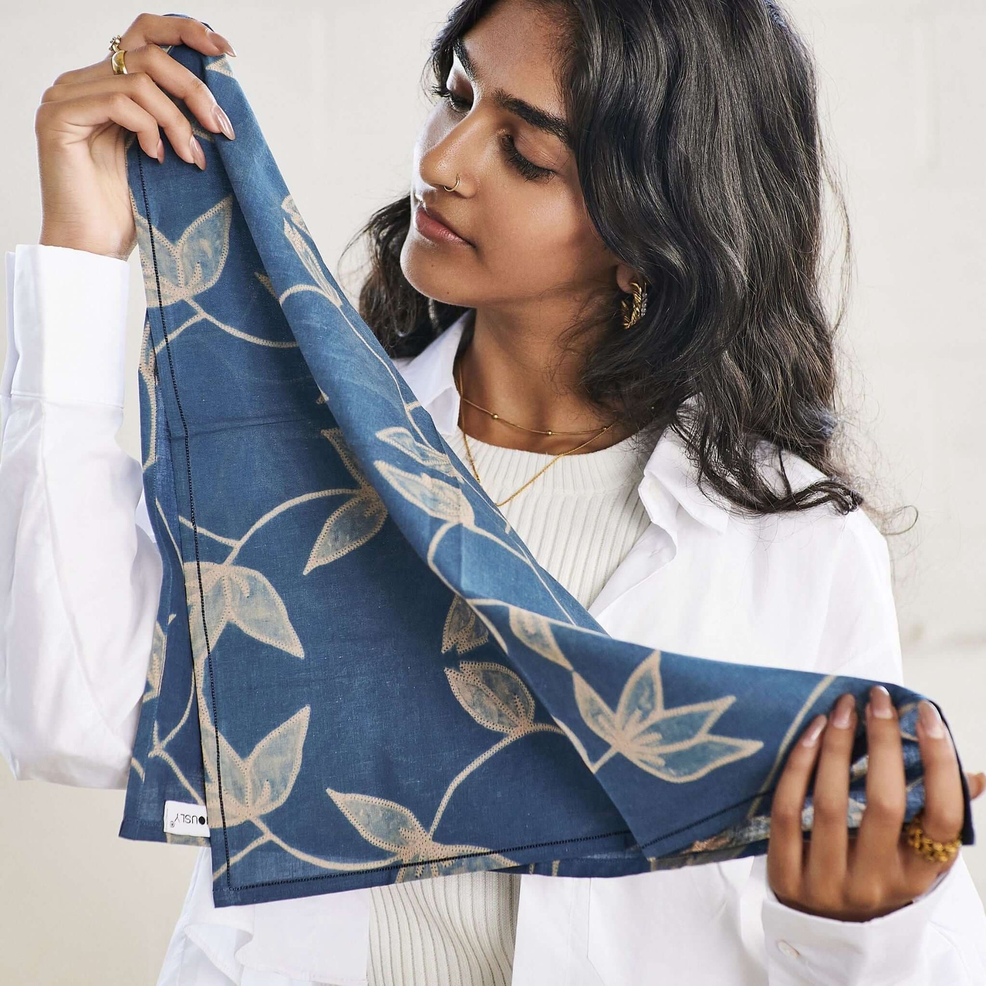 Folio Indigo Handcrafted Shibori Cotton Table Napkins ( set of 4 ) showcased by a model holding a beautifully dyed napkin.