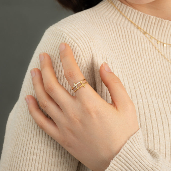 Hand wearing Golden Cross Serenity gold ring against a cream knit sweater