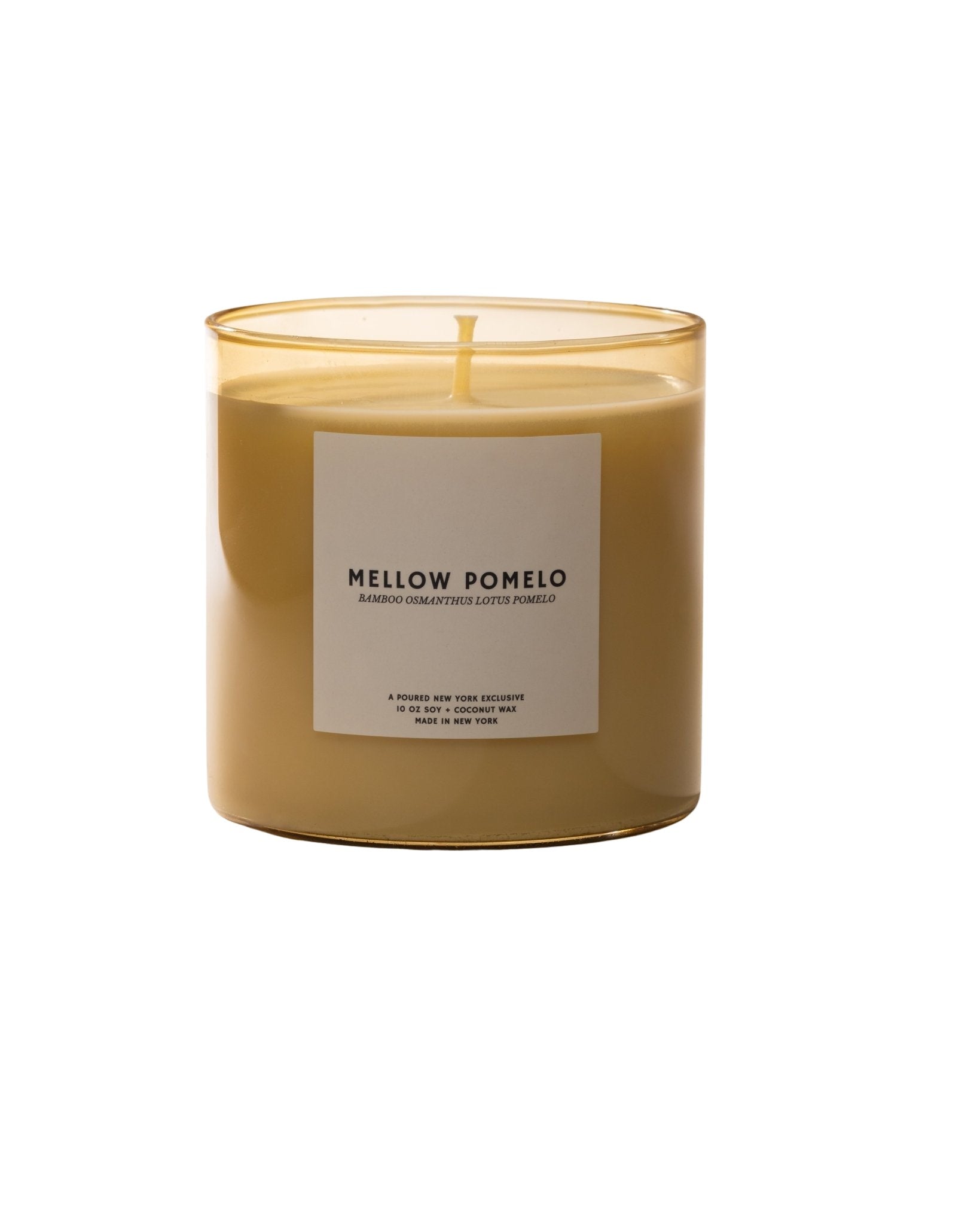 Candle labeled 'Mellow Pomelo' with packaging in the background on a neutral background