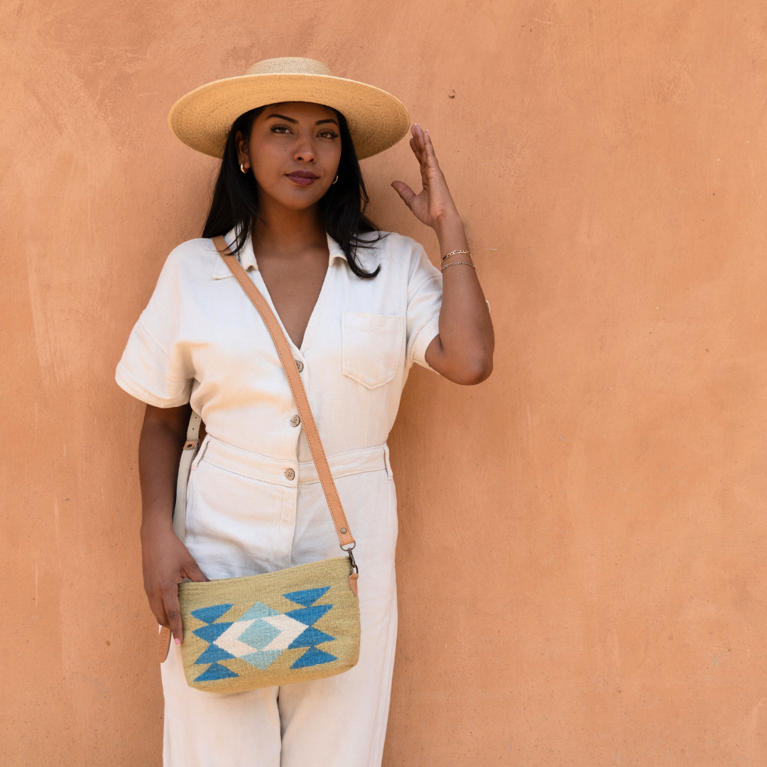 Woman wearing the handwoven convertible clutch with Zapotec butterfly design in bright spring colors; can be used as a pouch, wristlet, or crossbody with included leather straps and internal pocket