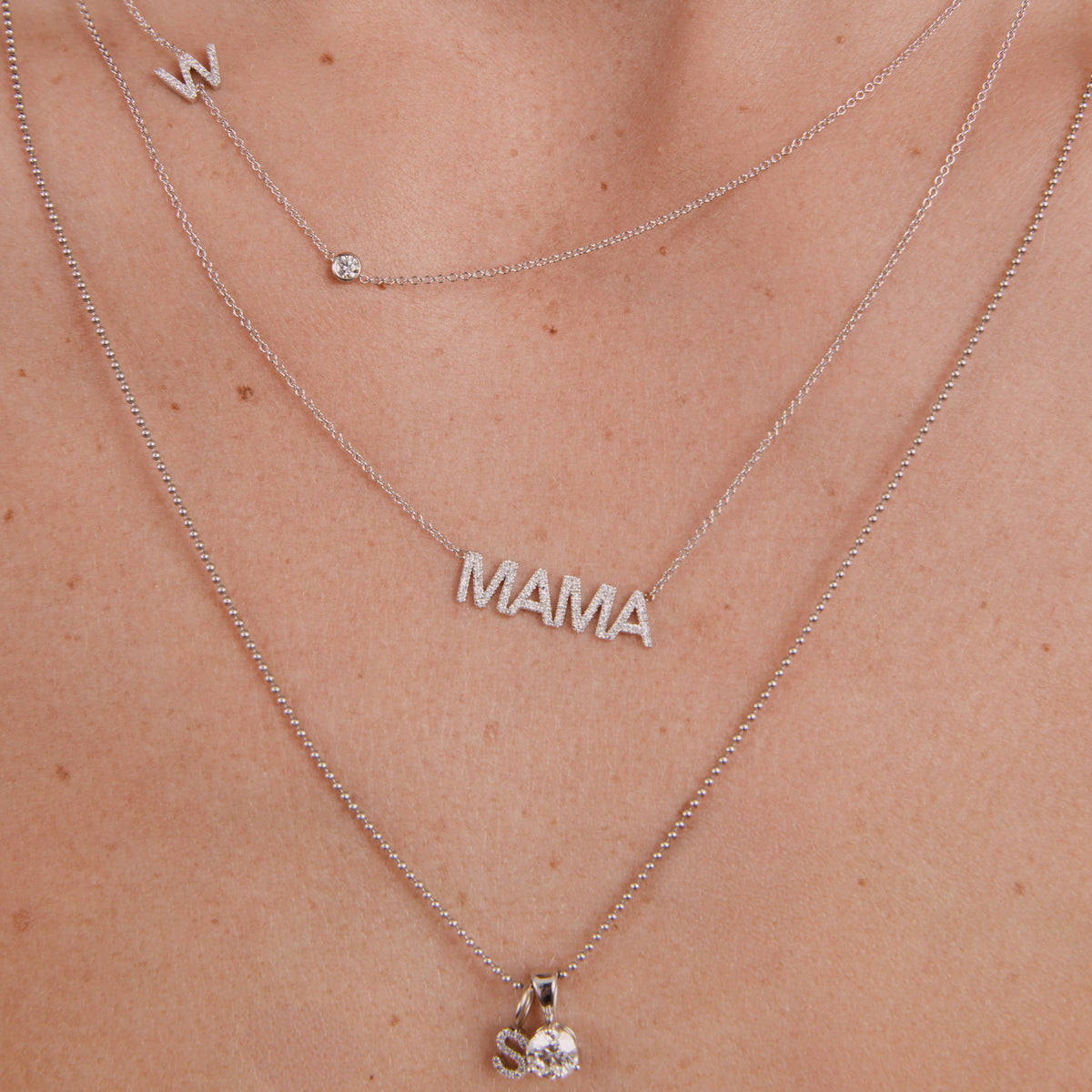 Silver 'MAMA' necklace on a person's neck with a close-up view.