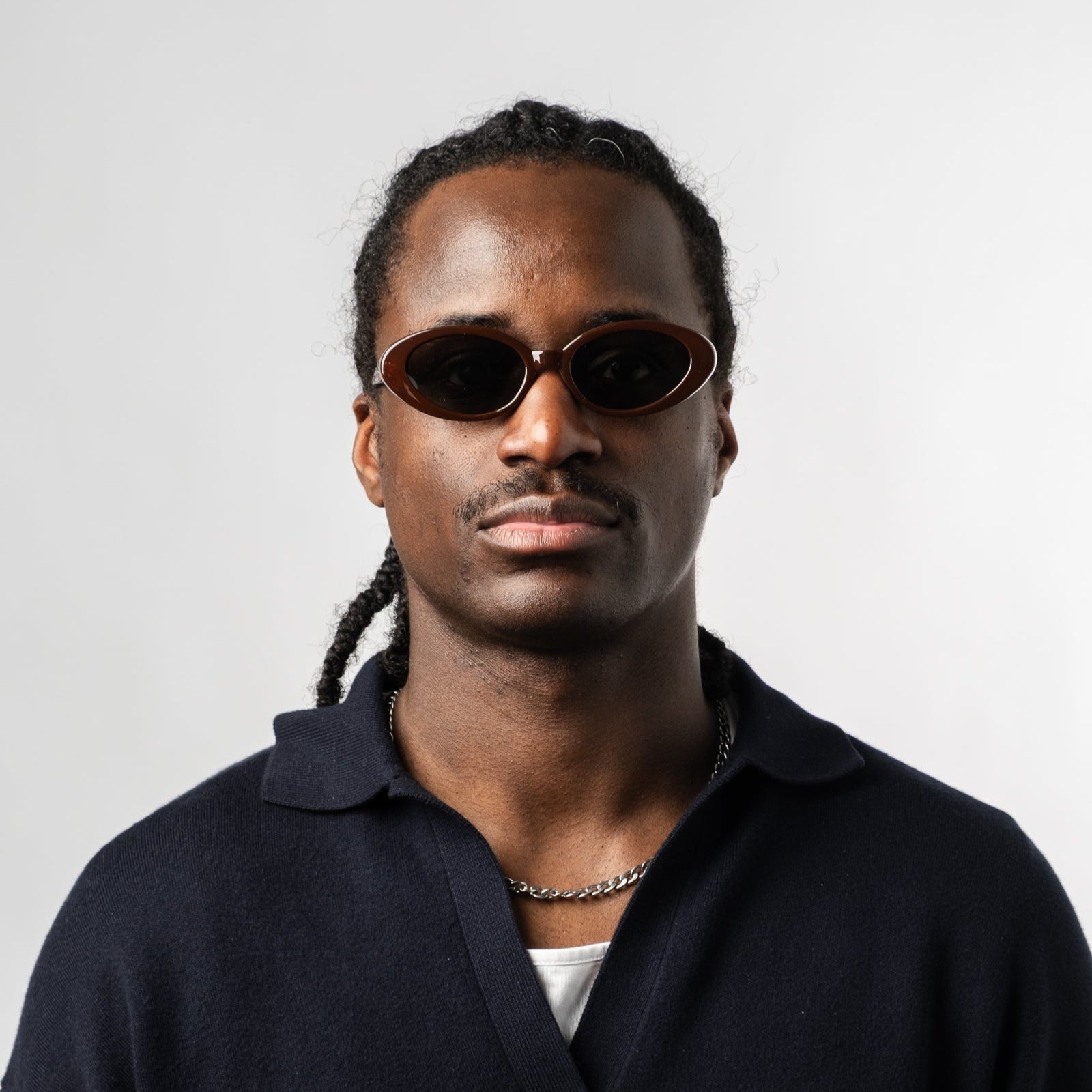 Male wearing Sad Eyewear Bloom oval sunglasses in tobacco red with tinted black lenses