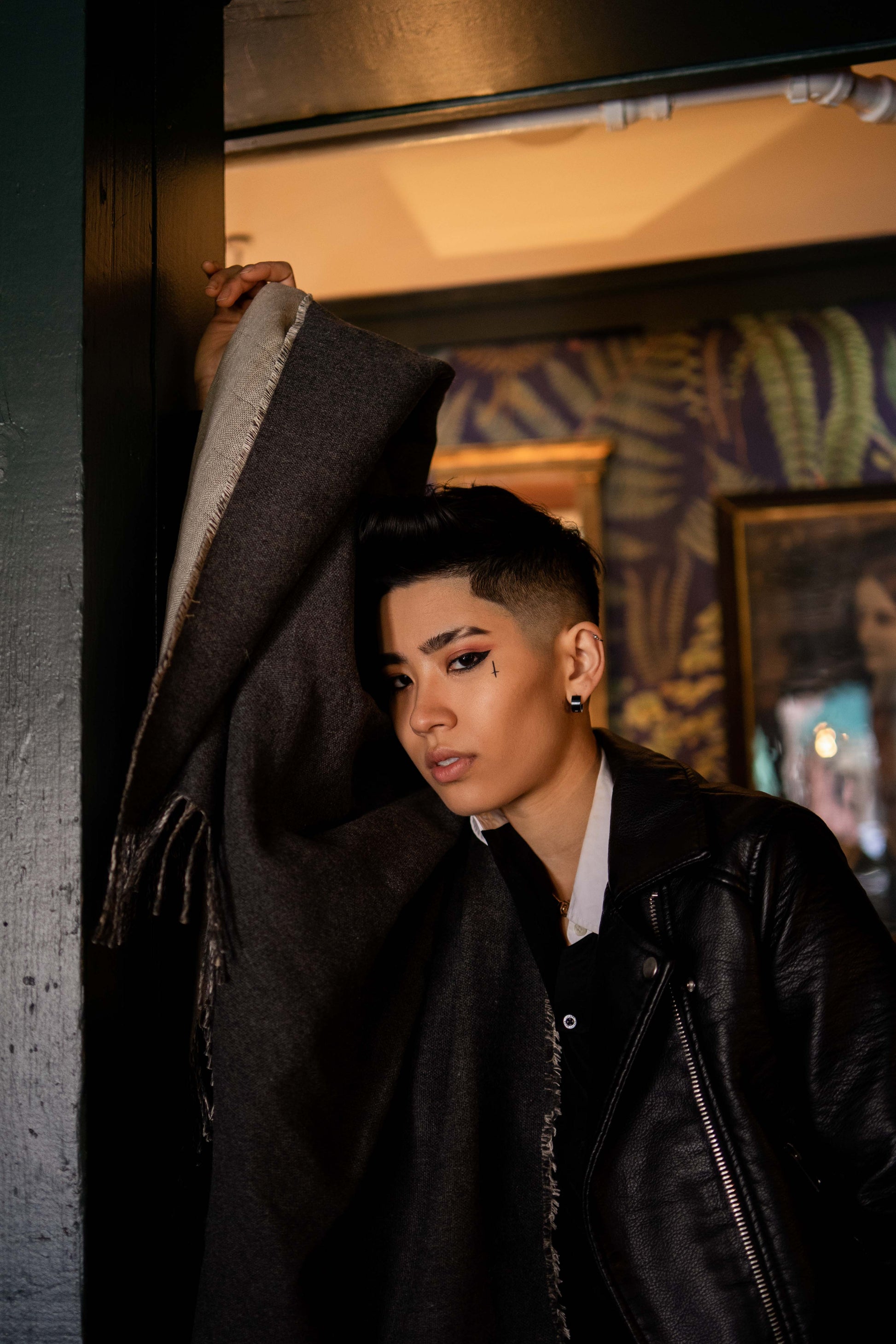 A stylish woman in a black jacket, showcasing Evangeline Linens' luxurious reversible oversized throw blanket made of linen and merino wool.