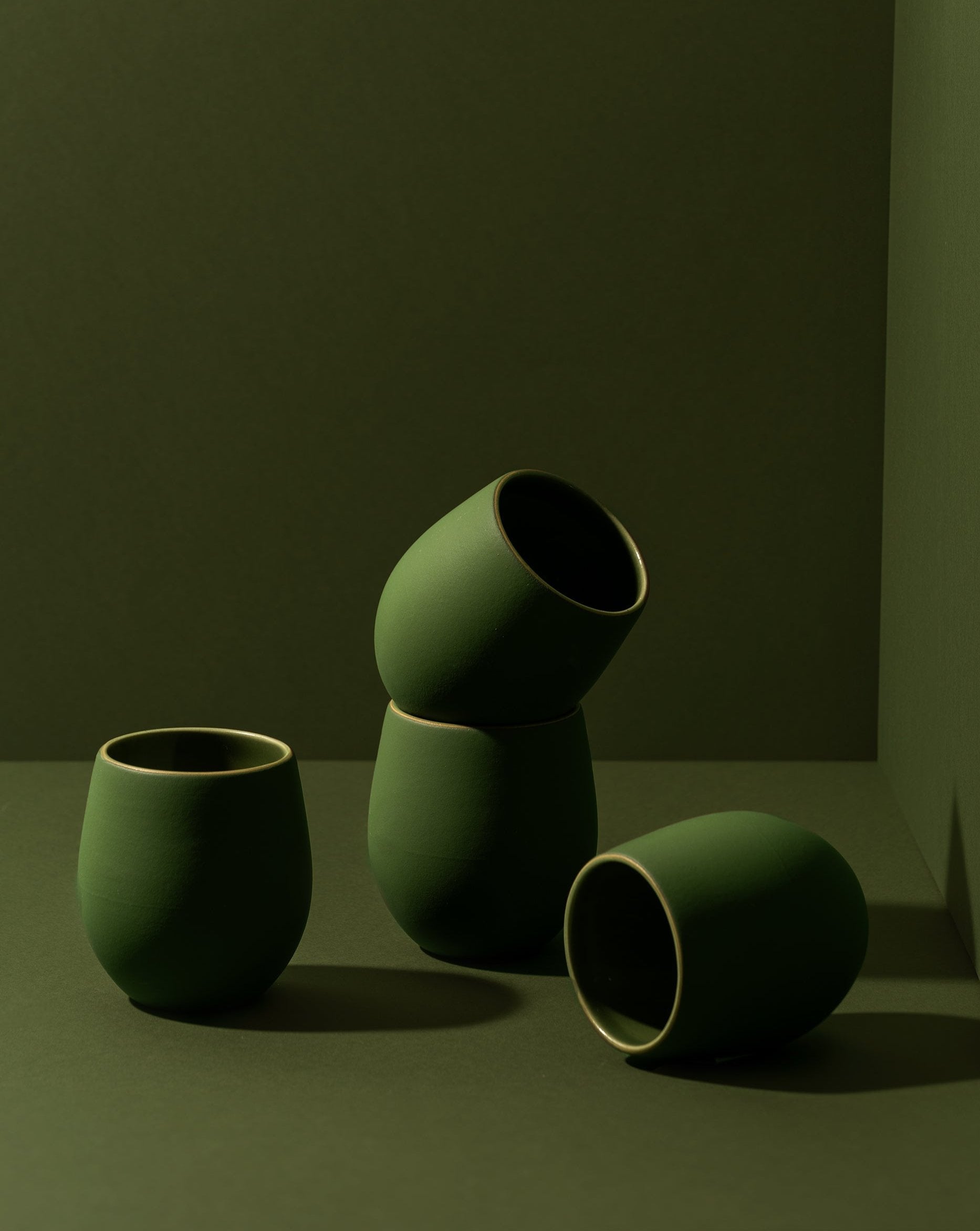 A set of four stoneware espresso tumblers in a neutral color, stacked in a pyramid shape against a neutral background.