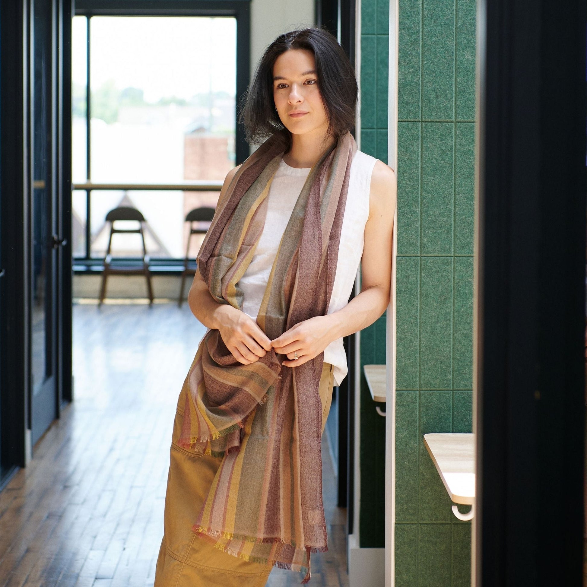Barque Clay Modern Artisan Striped Soft Merino Handwoven Scarf elegantly styled on a model in a bright, modern setting.