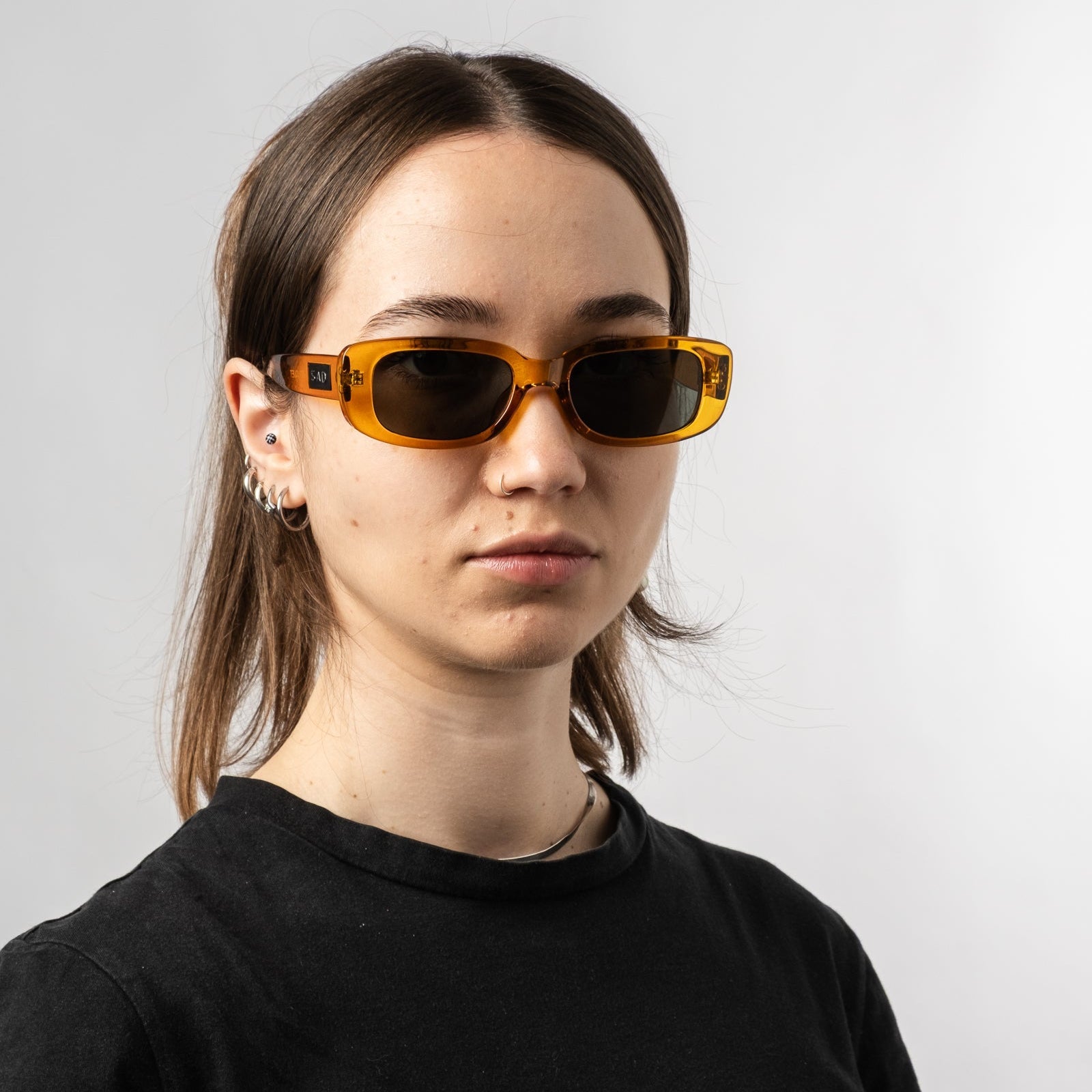 Female wearing Sad Eyewear Bouquet rectangle sunglasses in amber with UV protection lenses