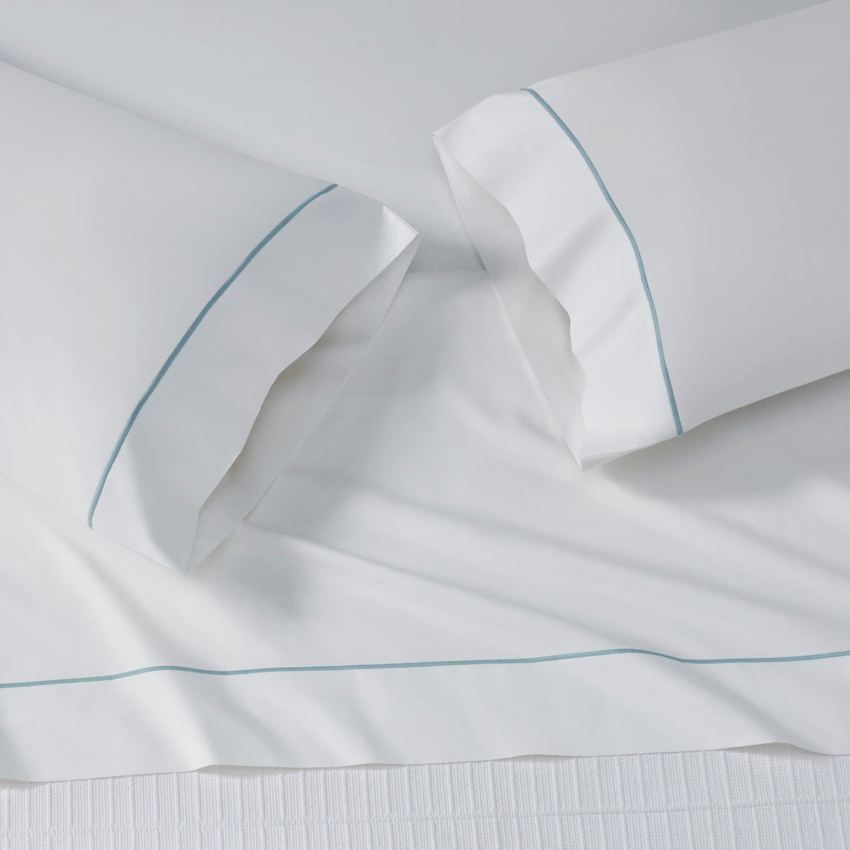 AKP-530-2040_3|White 100% cotton flat sheet and two pillowcases with sateen weave and light blue piping detail along the top border.