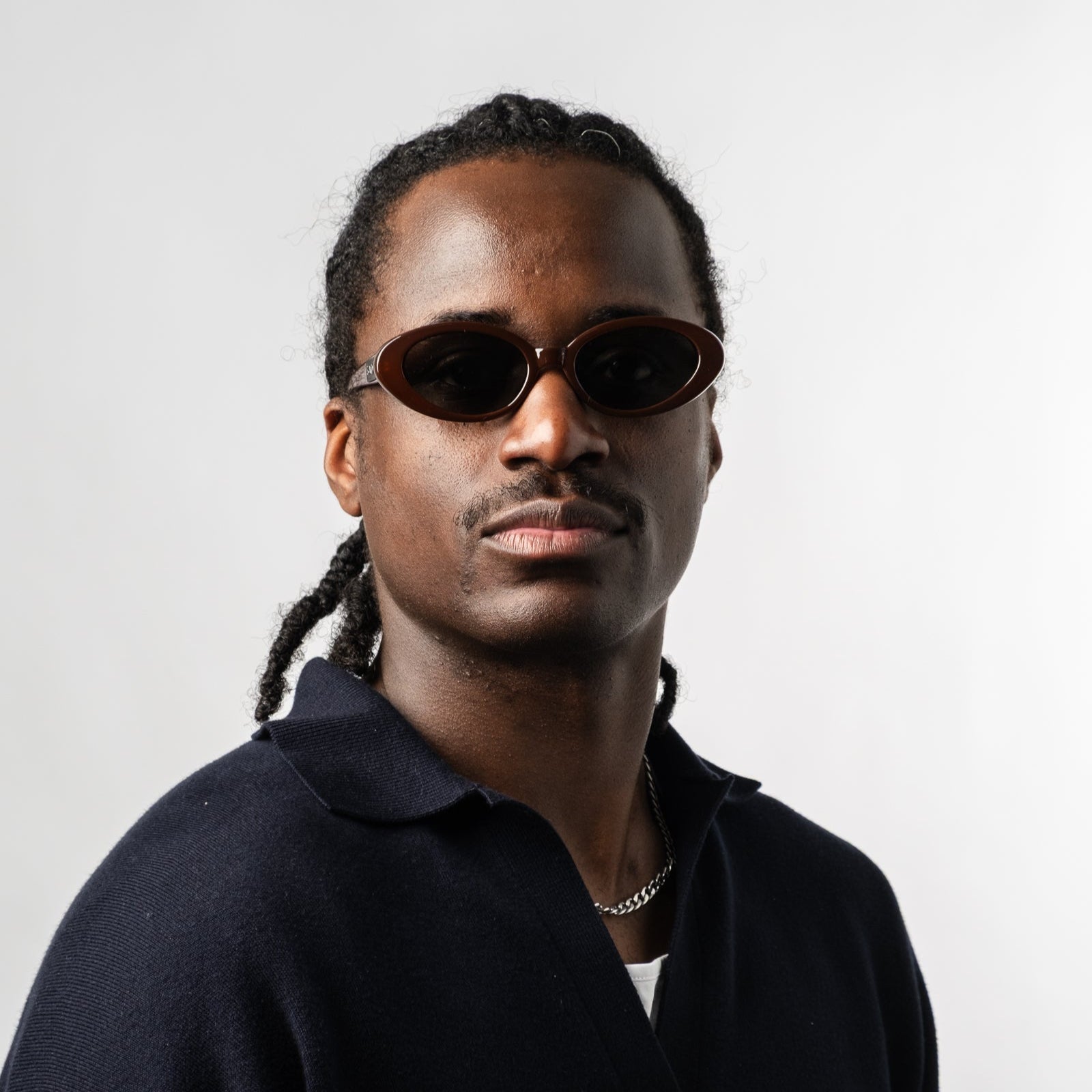 Male wearing Sad Eyewear Bloom oval sunglasses in tobacco red with tinted black lenses