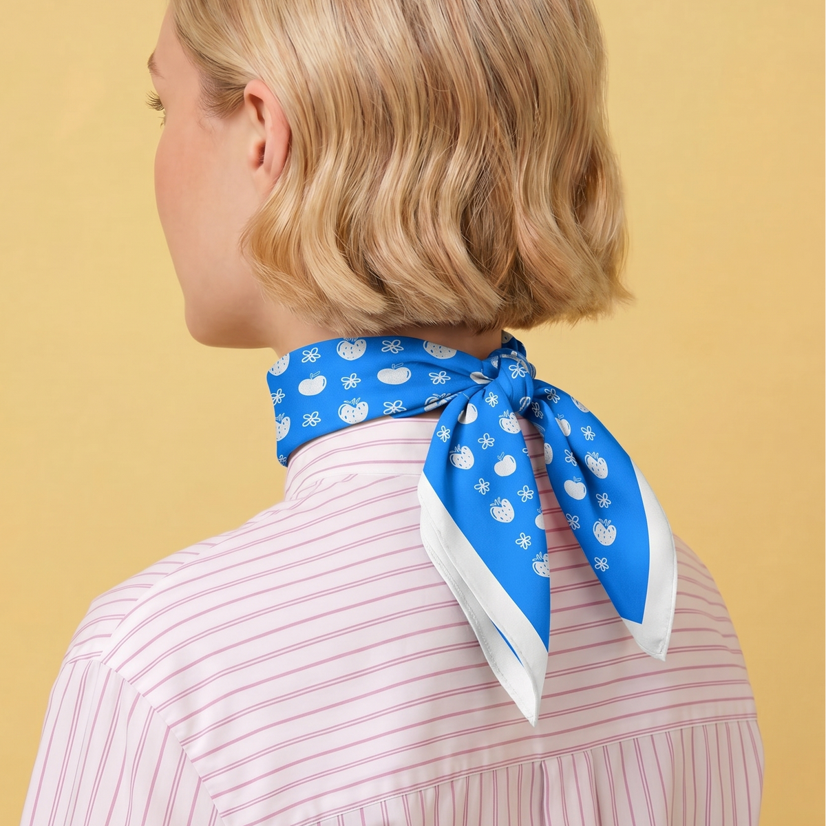 Person wearing a blue bandana with white flowers, apples and strawberries on a yellow background