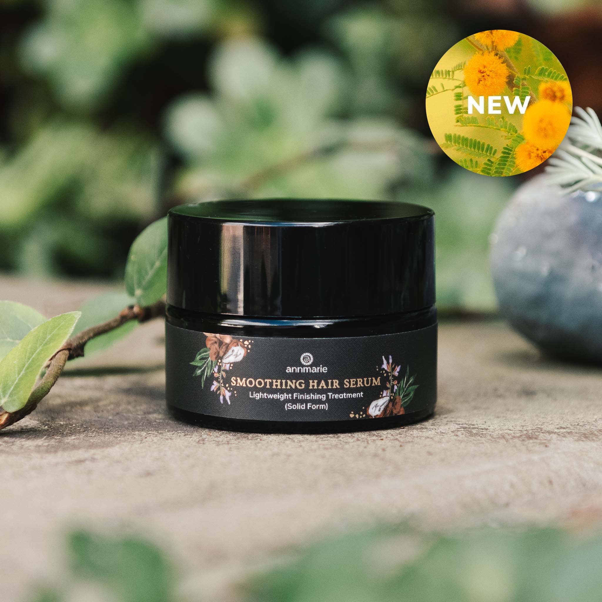 Smoothing Hair Serum lightweight finishing treatment in solid form, black jar displayed on a natural surface with greenery in the background and a “New” label.