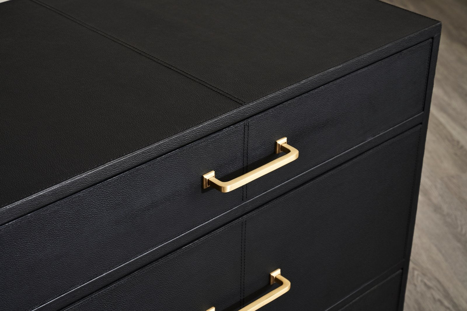 FN-5200-262028_7|Close-up of the top two drawers of a black leather furniture dresser with gold handles, showcasing premium craftsmanship.