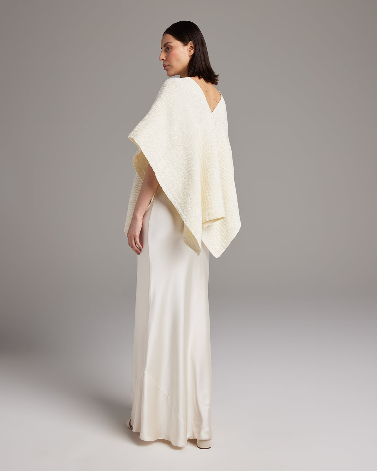 Model wearing a cream Manta Captiva poncho, back view