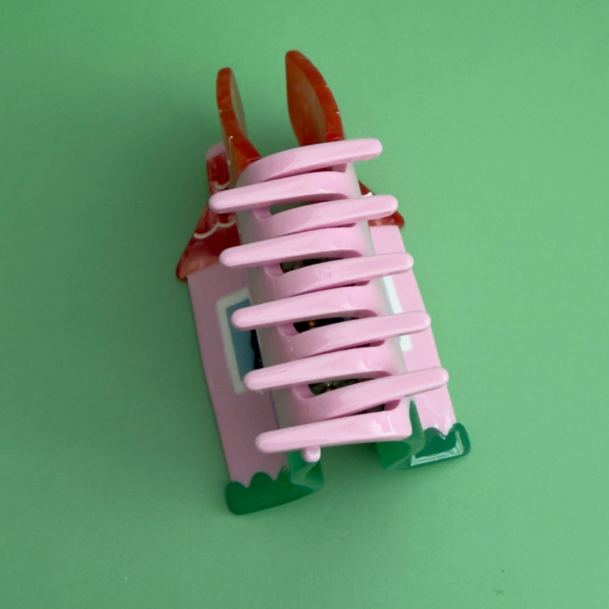 This charmin house hair claw, comes with an extra purr-k: a resident feline who will charmingly oversee the neighborhood from their sun-drenched window perch.

This practical yet cozy house hair claw, will hold strong as it's pink foundation. 

Who says you can afford a house! hehe, now you can! 