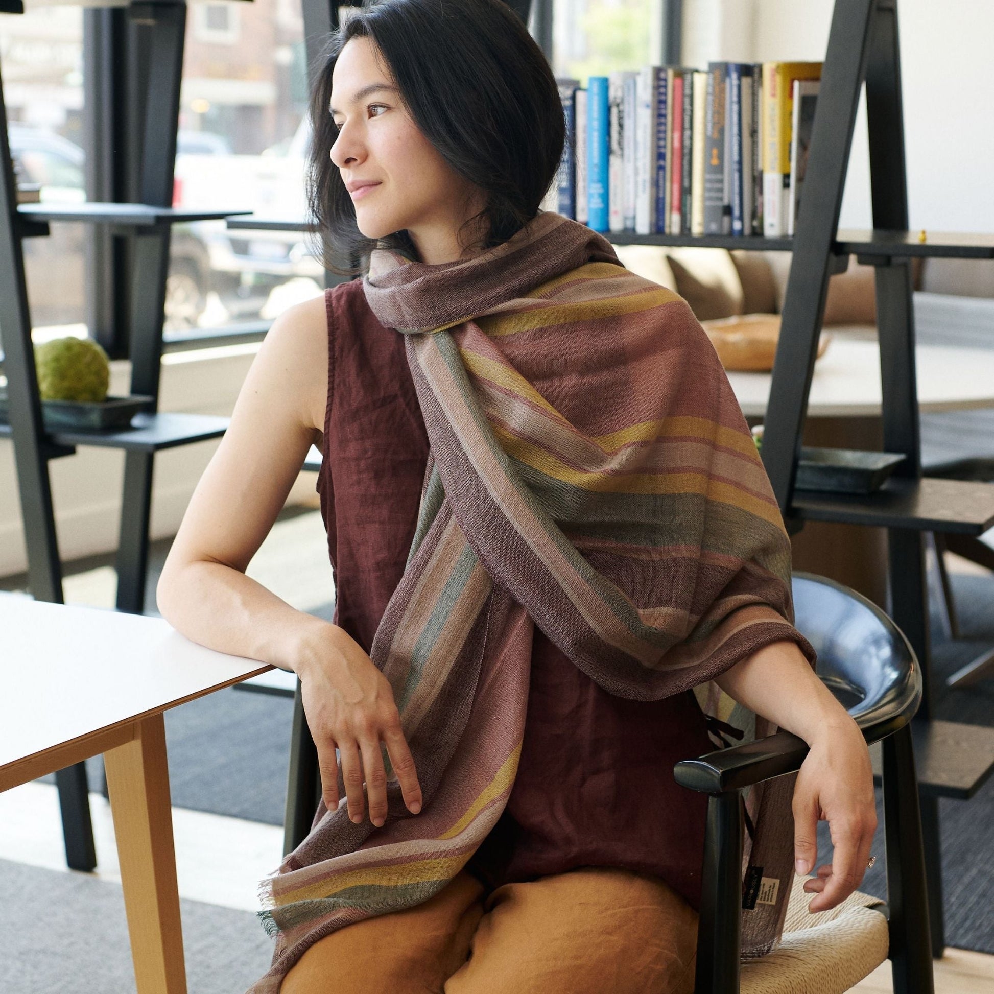 Woman wearing Barque Clay Modern Artisan Striped Soft Merino Handwoven Scarf in a stylish indoor setting.
