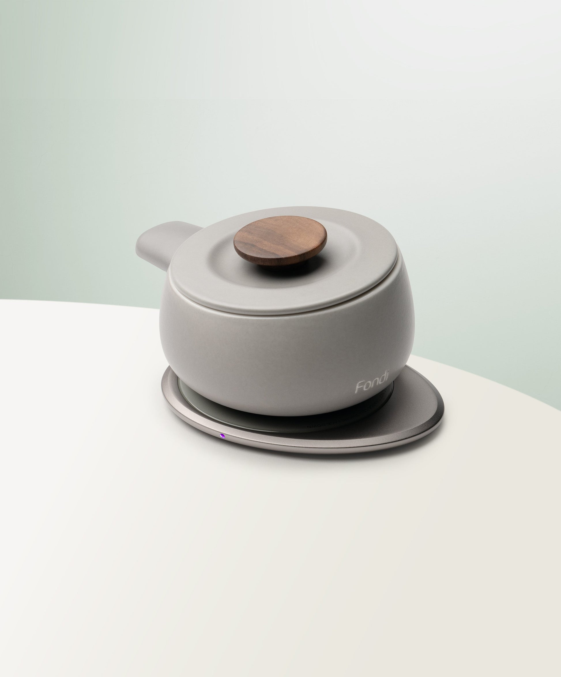 Fondi Self-Heating Ceramic Fondue 7.6 fl oz / 225 mL in Soft Gray angled top-side view on OHOM Charging Pad 3