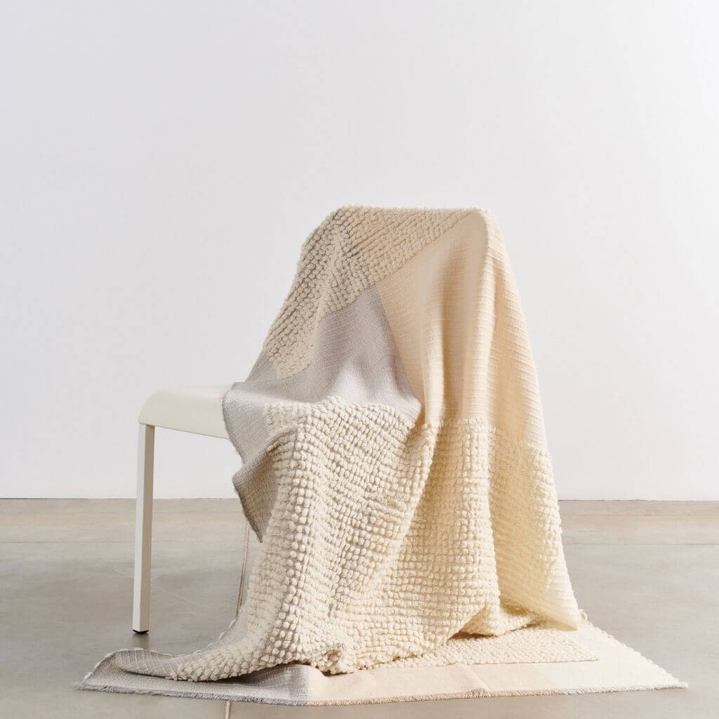 Butterscotch White Handloom Textured Plush Merino Throw draped over a chair showcasing its luxurious texture and design.