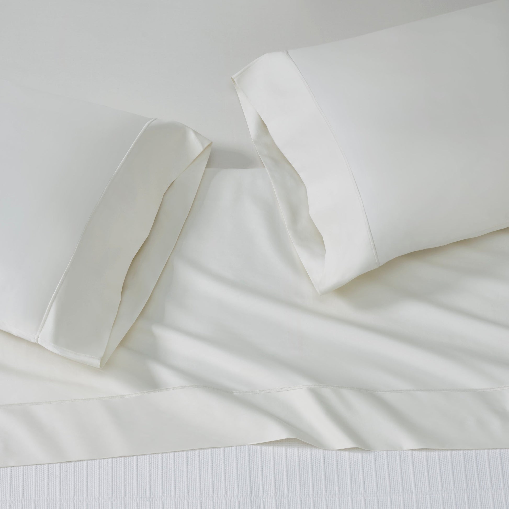 ASP-545-2032_2|Top-down view of off-white 100% cotton flat sheet and two pillowcases, plain weave, with a simple hem border.