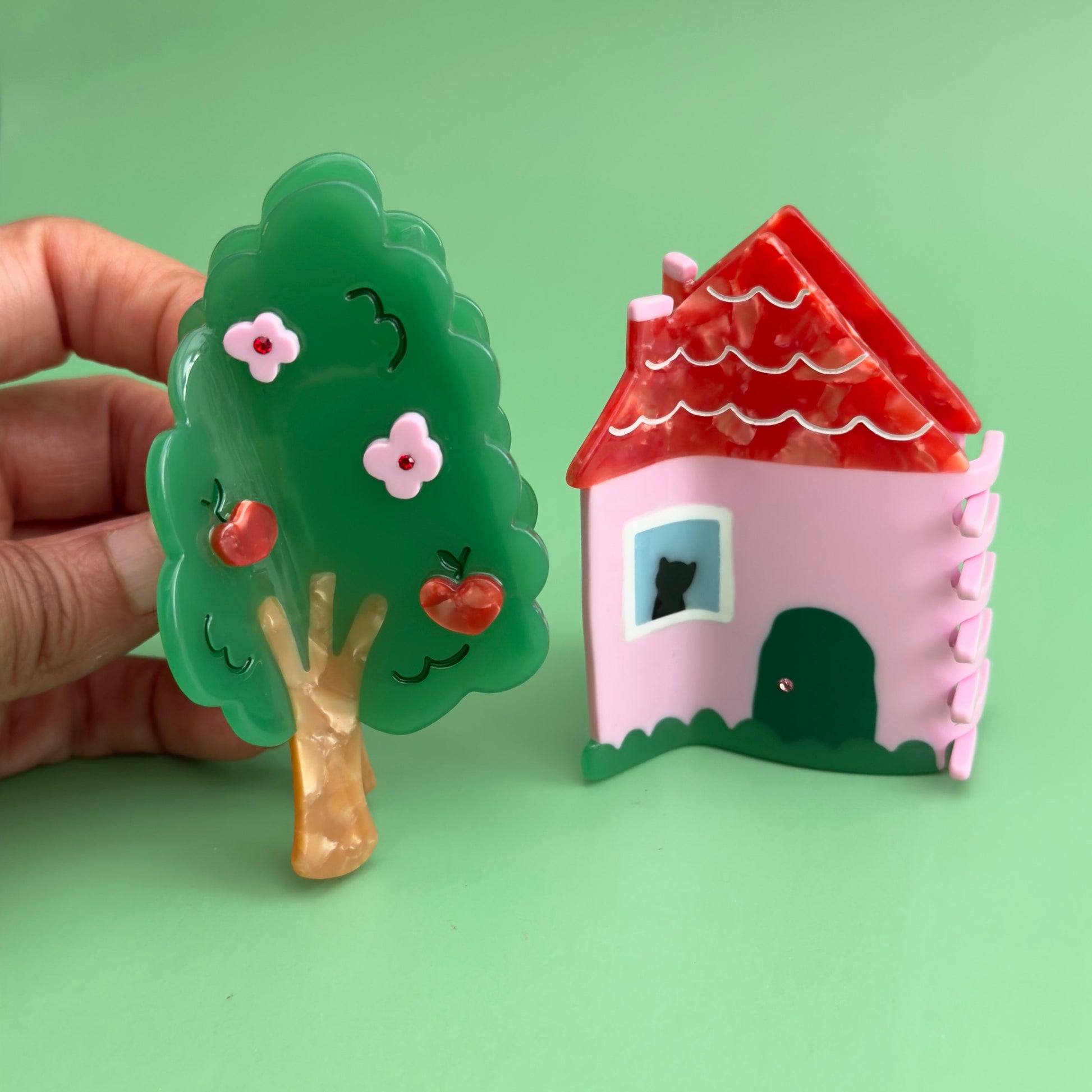 This charmin house hair claw, comes with an extra purr-k: a resident feline who will charmingly oversee the neighborhood from their sun-drenched window perch.

This practical yet cozy house hair claw, will hold strong as it's pink foundation. 

Who says you can afford a house! hehe, now you can! 