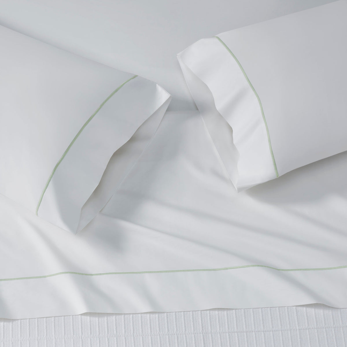ASP-533-2032_5|Stack of five folded white 100% cotton flat sheets or pillowcases, each with a different colored piped border.
