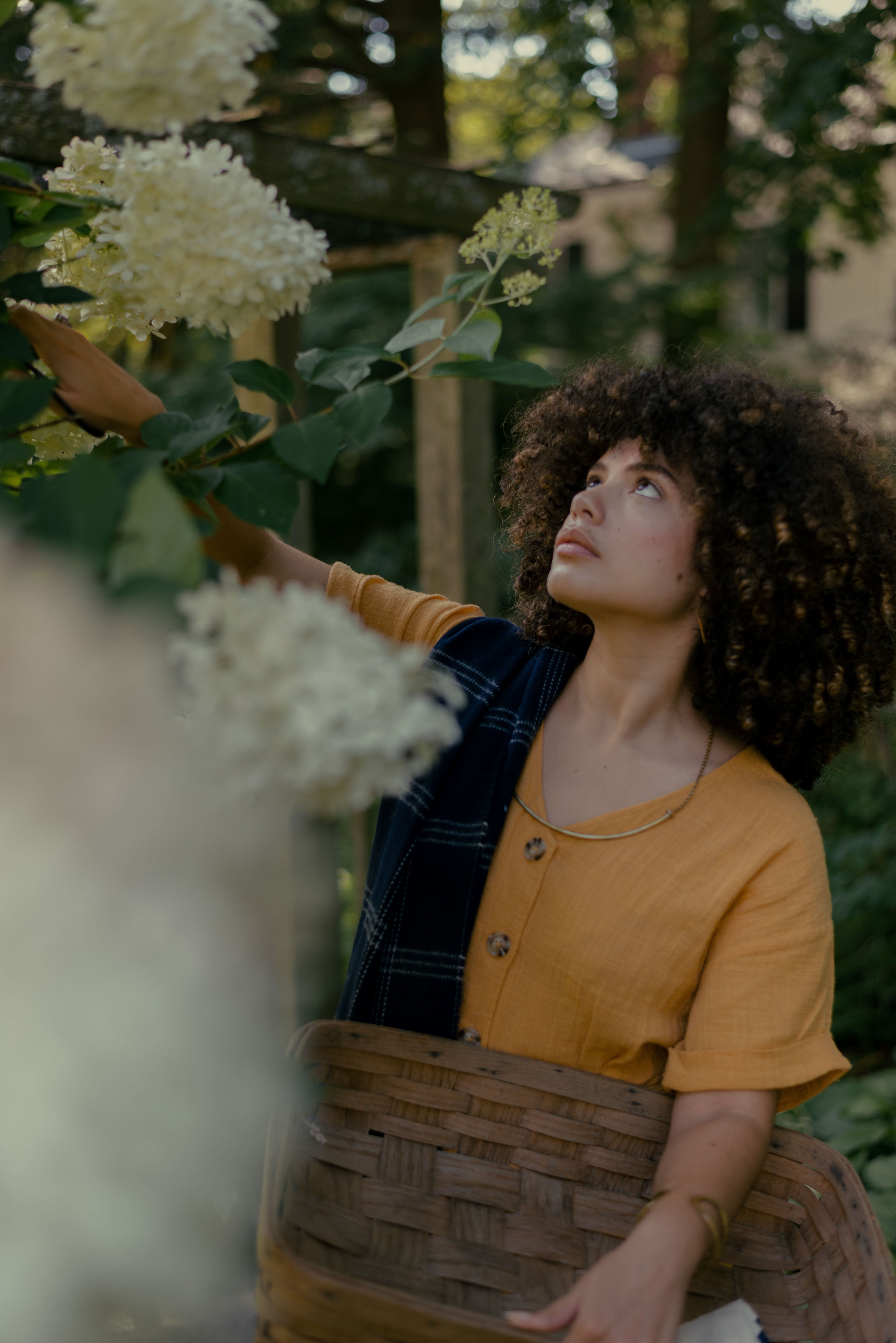 A luxurious woman with luscious curly hair, adorned in a merino wool wearable wrap, showcasing the elegance of Evangeline linens.
