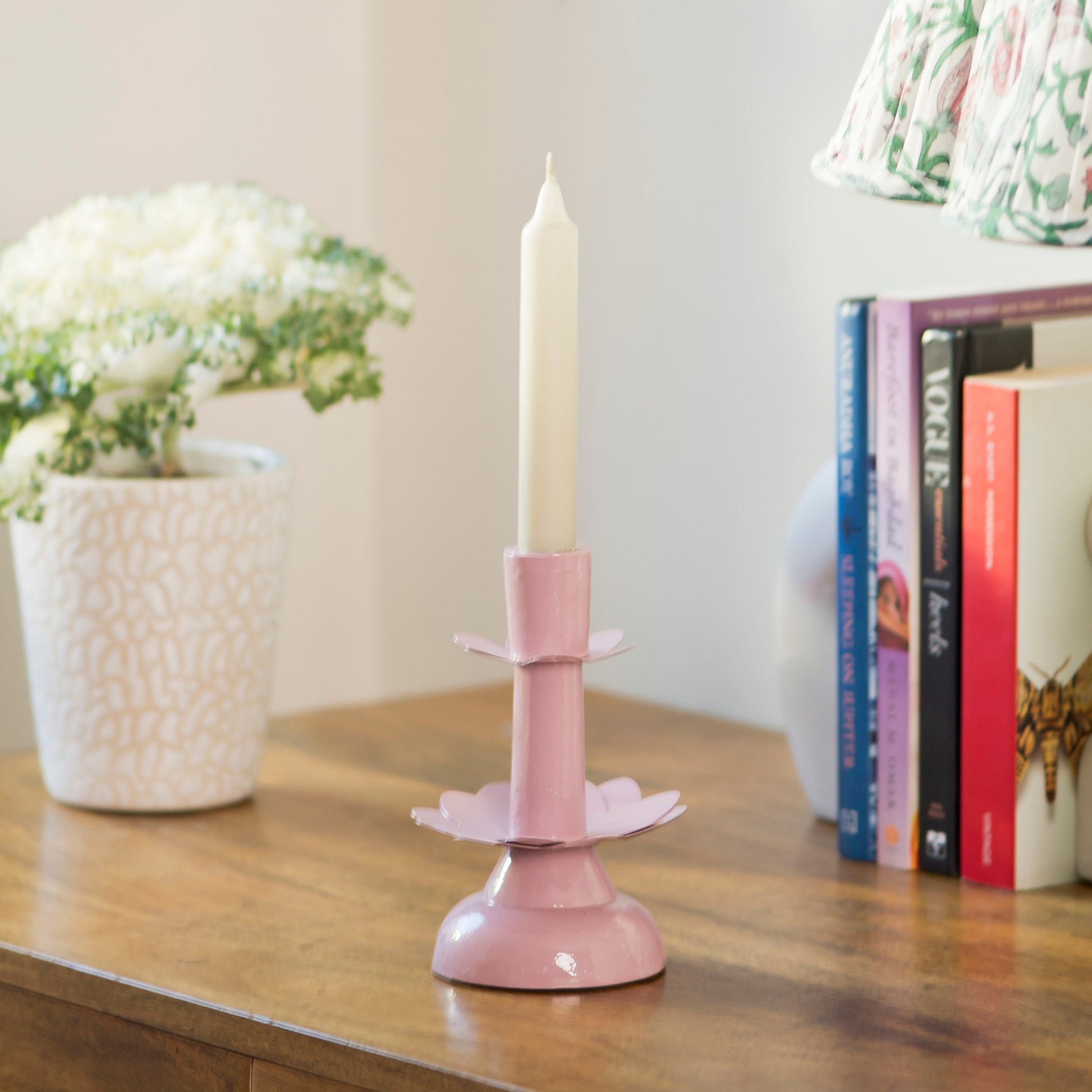 Artisanal pink aluminum floral candlestick holder on a dining table for spring or wedding decor.