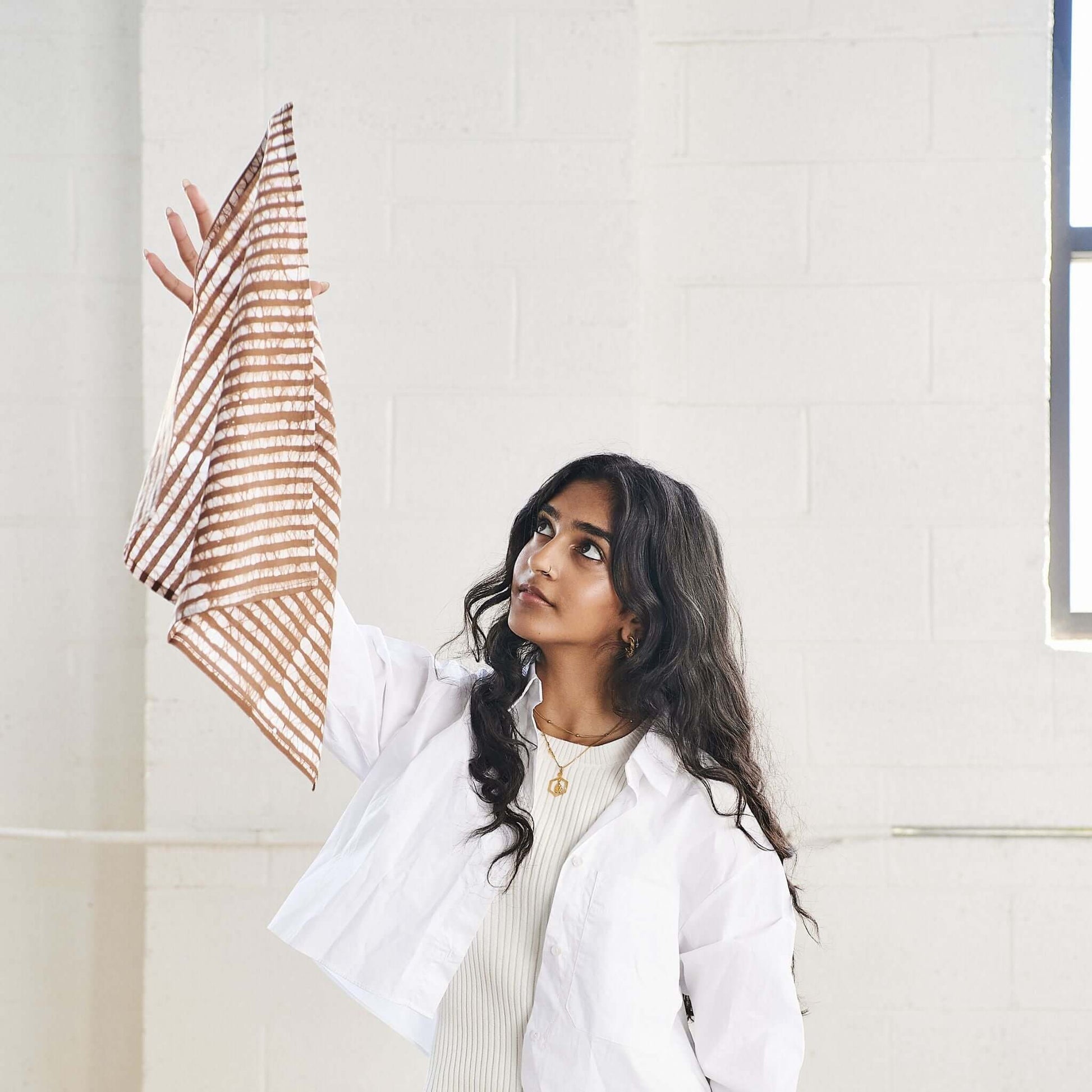 Model holding Oak Brown Stripes Wax Block Print Cotton Table Napkin set of 4, showcasing its unique design and artisanal quality.