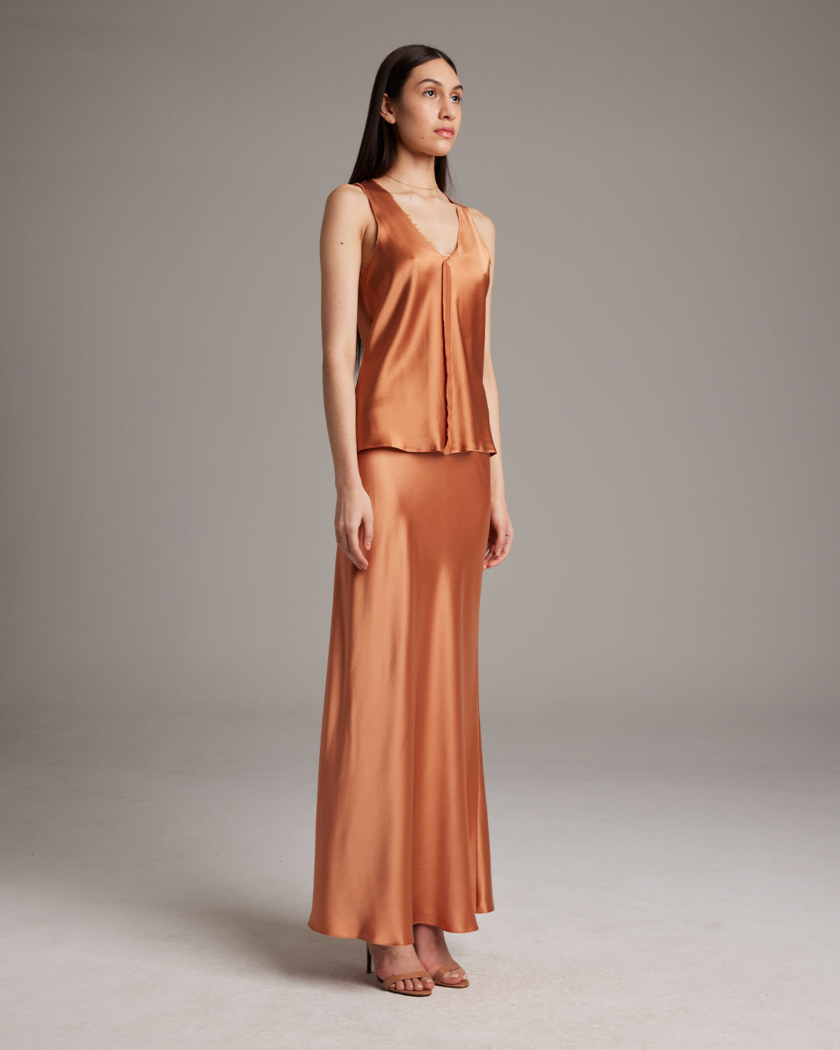 Model wearing a silk raw edge tank top in terracotta color