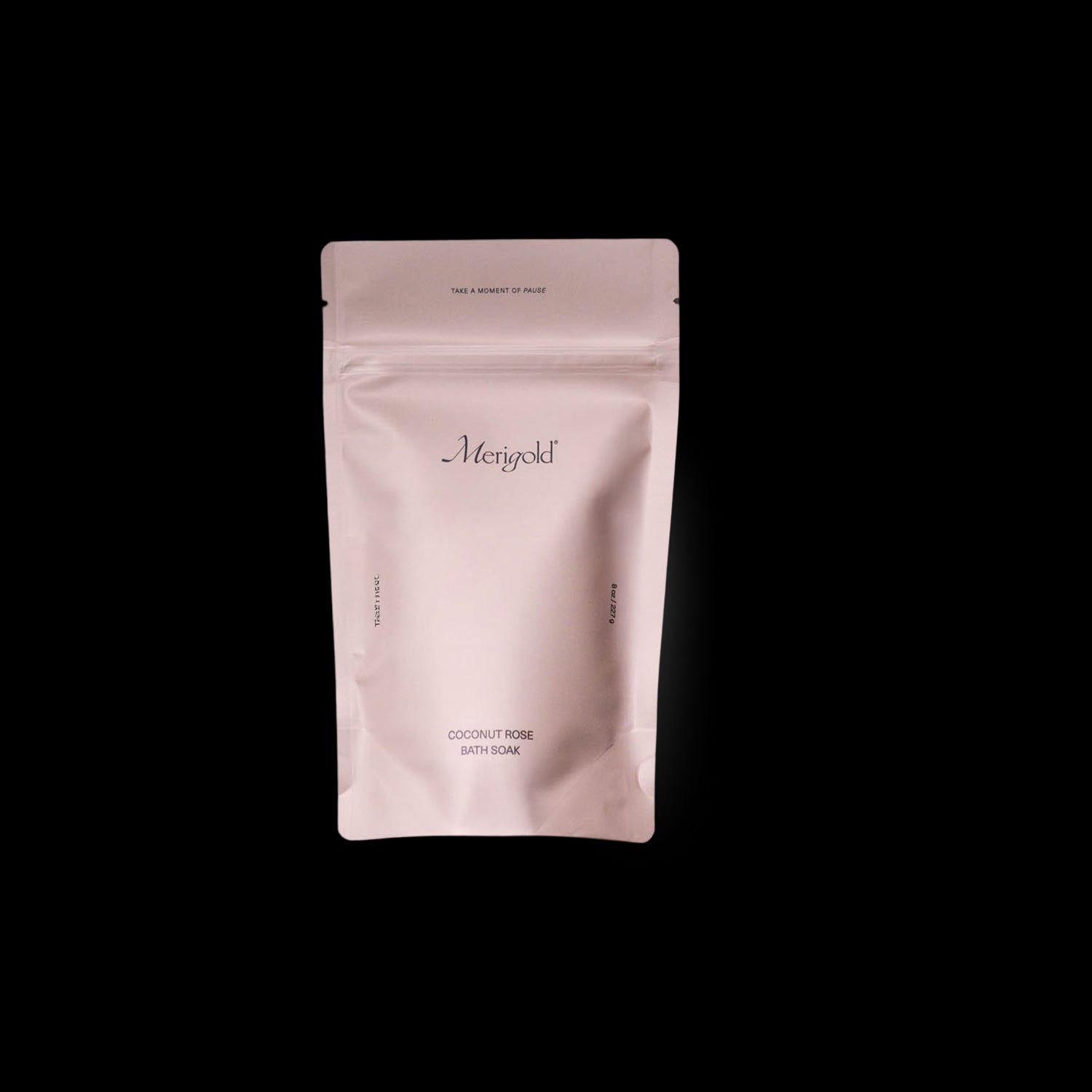 Merigold Coconut Rose Bath Soak is in a dusty rose colored resealable bag, featuring minimalist design and ingredients like organic coconut milk and dried rose petals. Photographed on a white background. 
