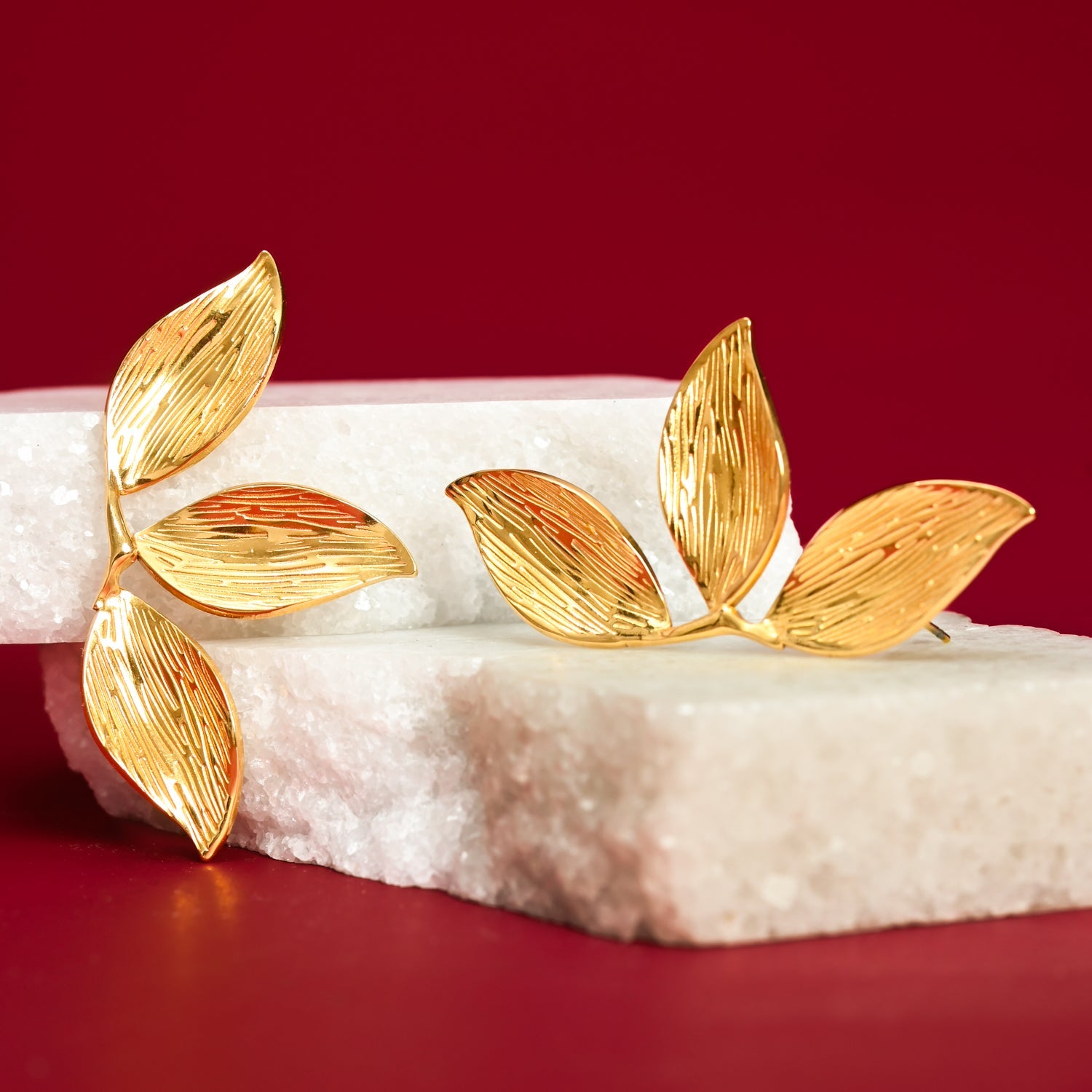 Photo of gold earrings with red background on white marble platform, 14k gold, golden canopy earrings, mother's day presents
