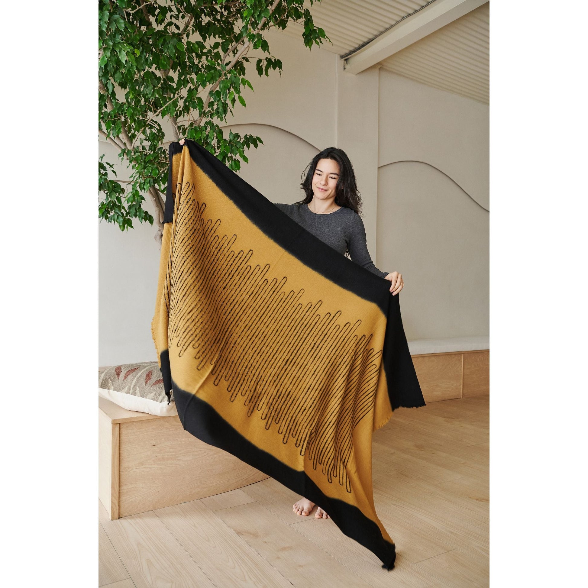A person holding the Handwoven Topaz Brown Myrtle Drift Merino Throw showcasing its unique pattern and warm colors.