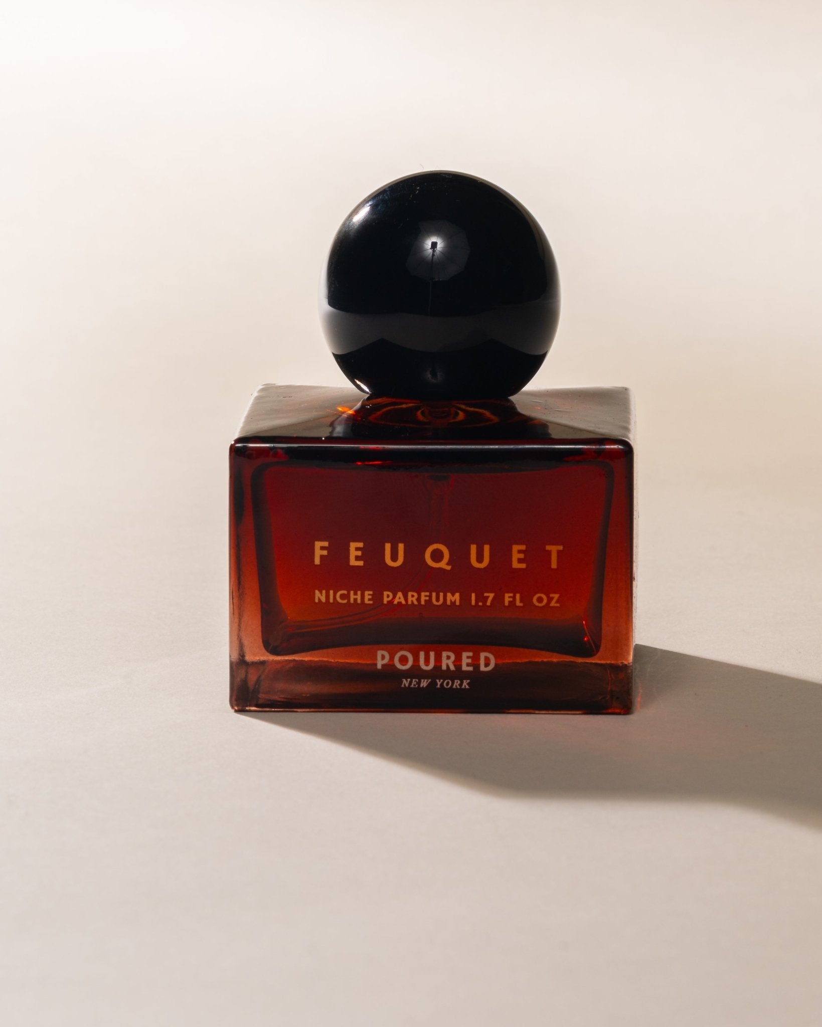 Poured New York ' Feuquet' red niche parfum square bottle with black cap on a neutral background
