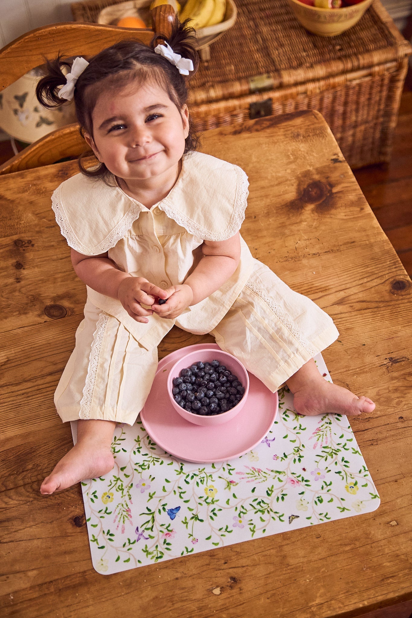 Smily toddler eating blueberries from pink Recette dishes