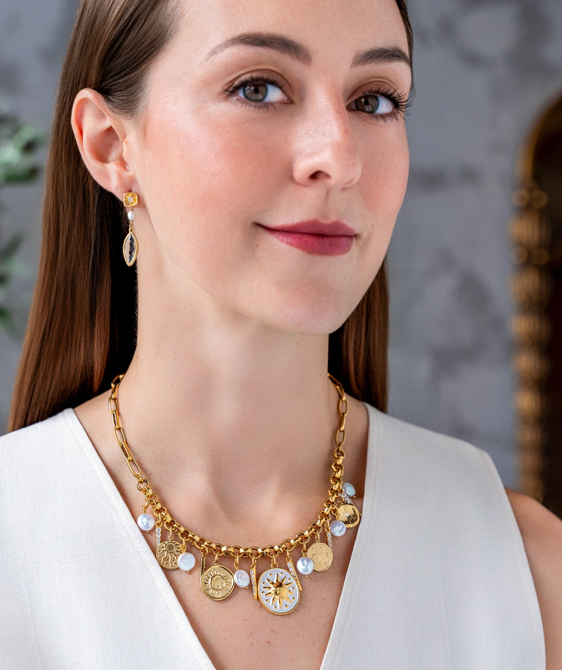 Gold celestial charm necklace with sun medallions, coin pearls, pavé crystal accents, and dangling celestial charms on a chunky chain.