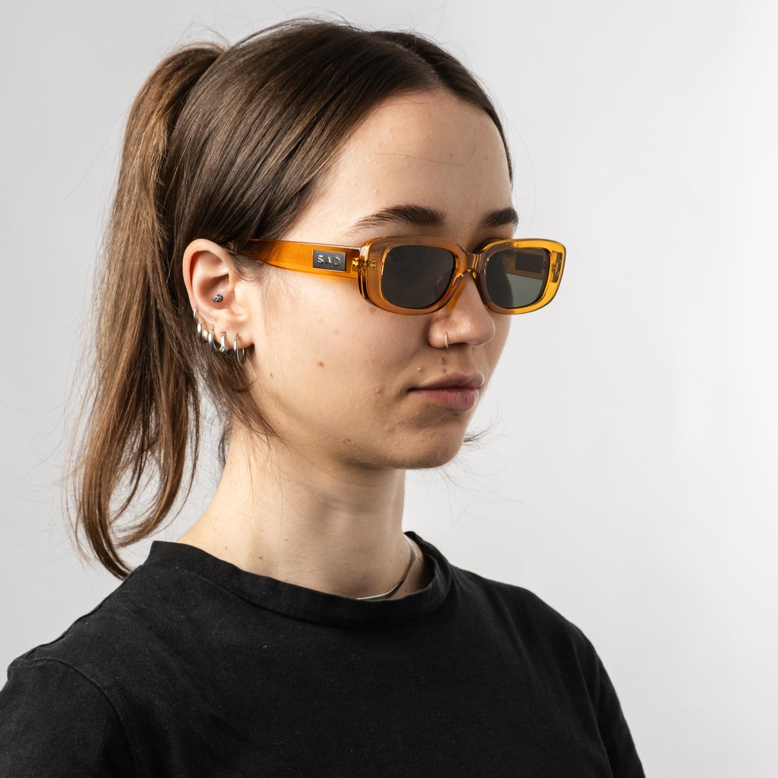 Female wearing Sad Eyewear Bouquet rectangle sunglasses in amber with UV protection lenses