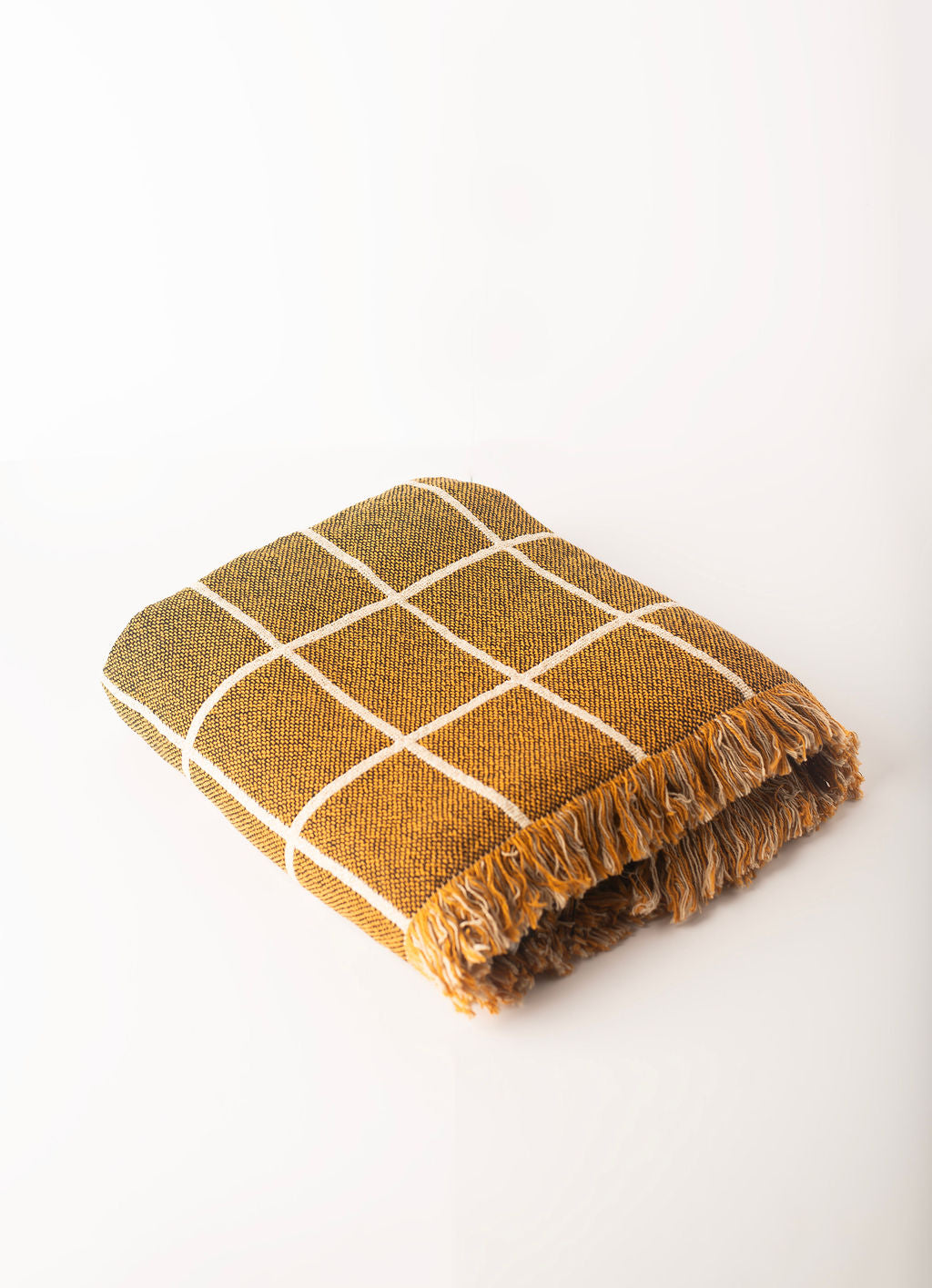 Close-up of Greer Acorn golden brown and cream windowpane grid woven cotton throw with fringe