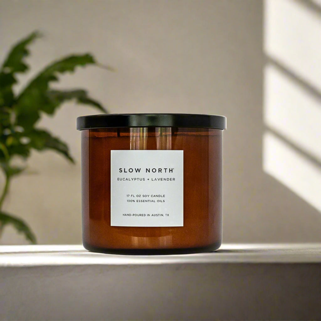 large amber jar candle with black lid