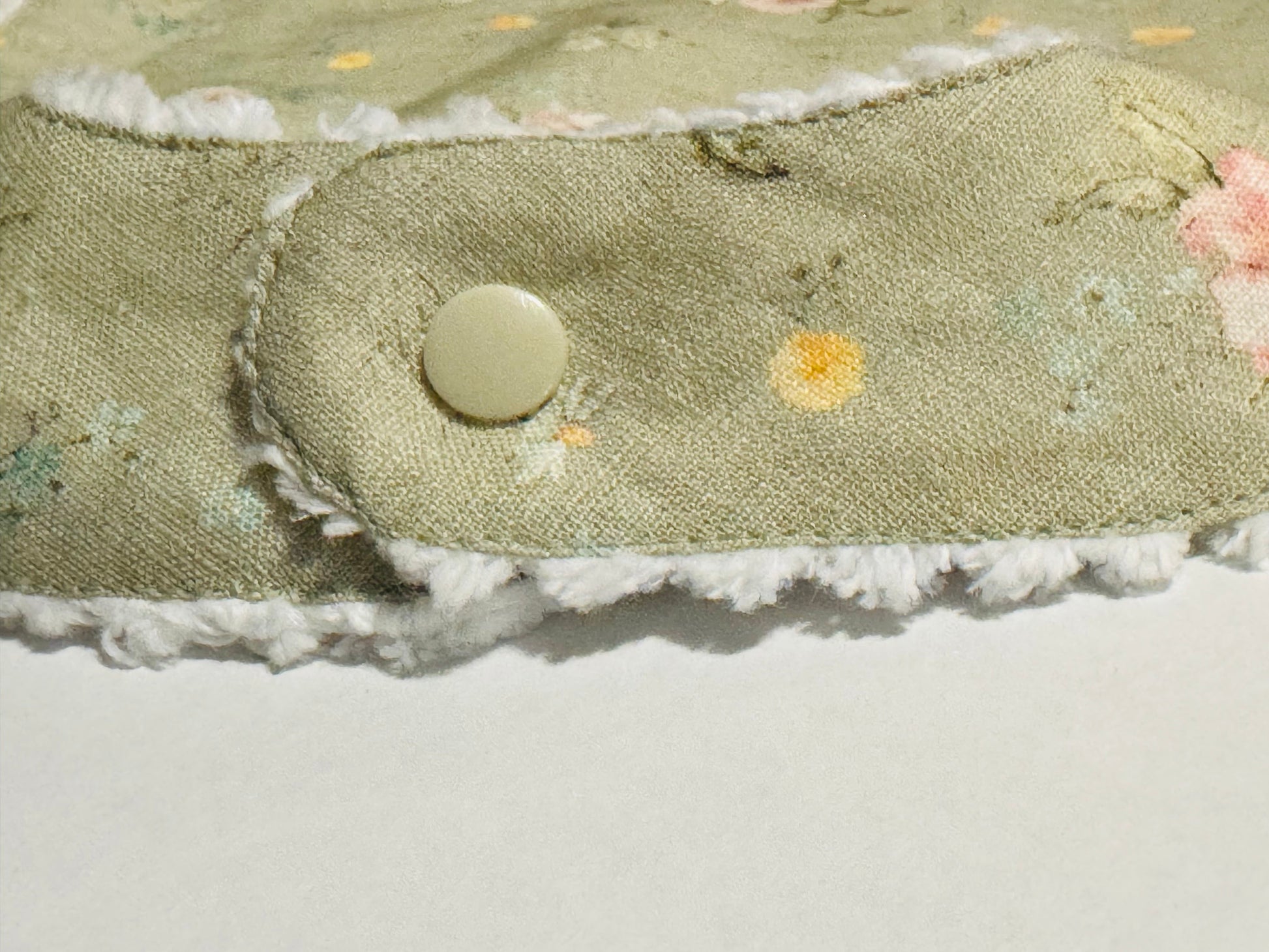 Line Bib back snap closure with floral embroidery and a button on a light background