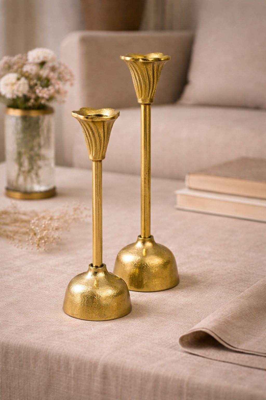 Two gold candle holders on a beige surface with a blurred background
