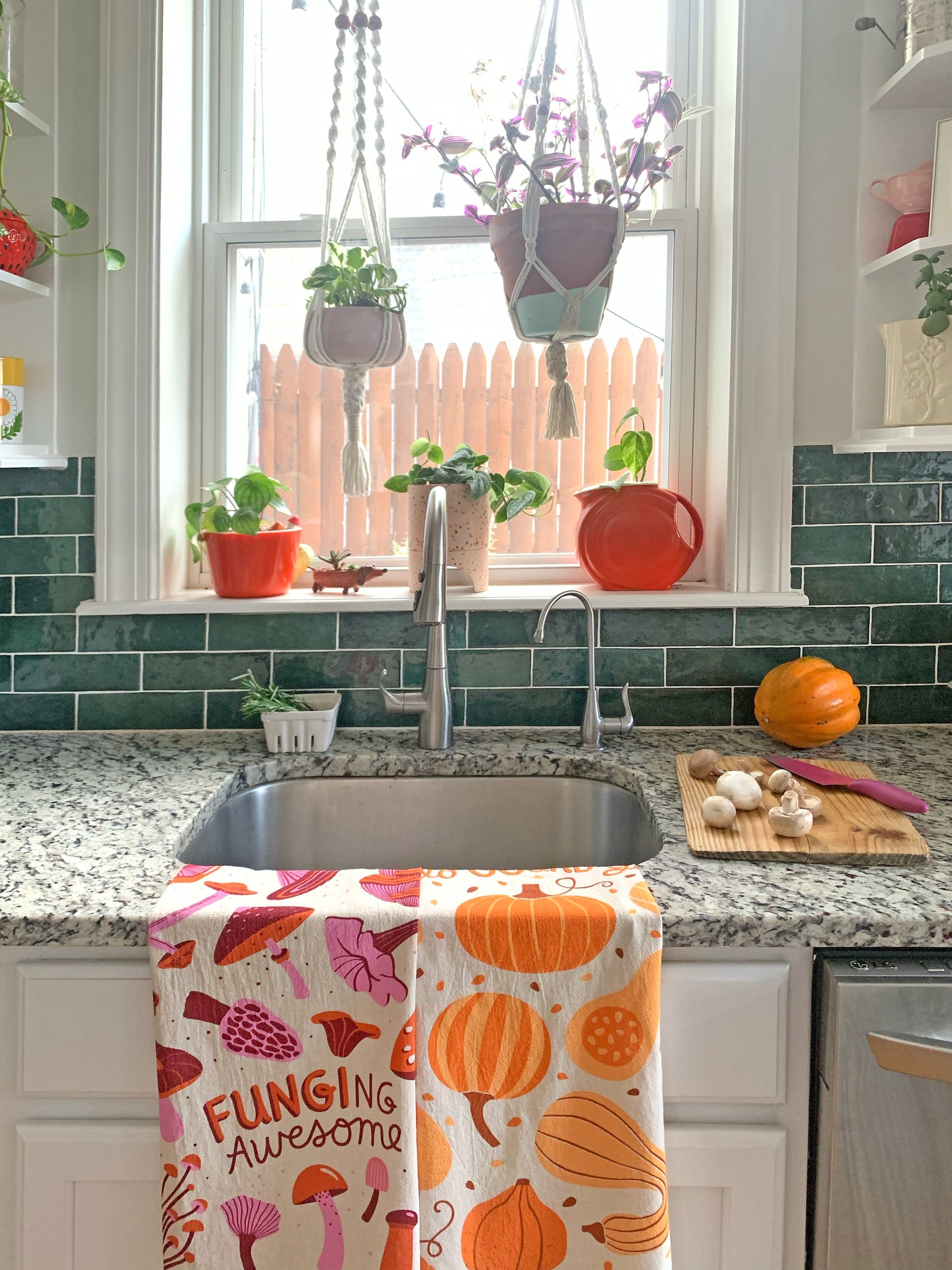 Mushroom and gourd towels folded over kitchen sink, with gourds and mushrooms on a cutting board on the counter