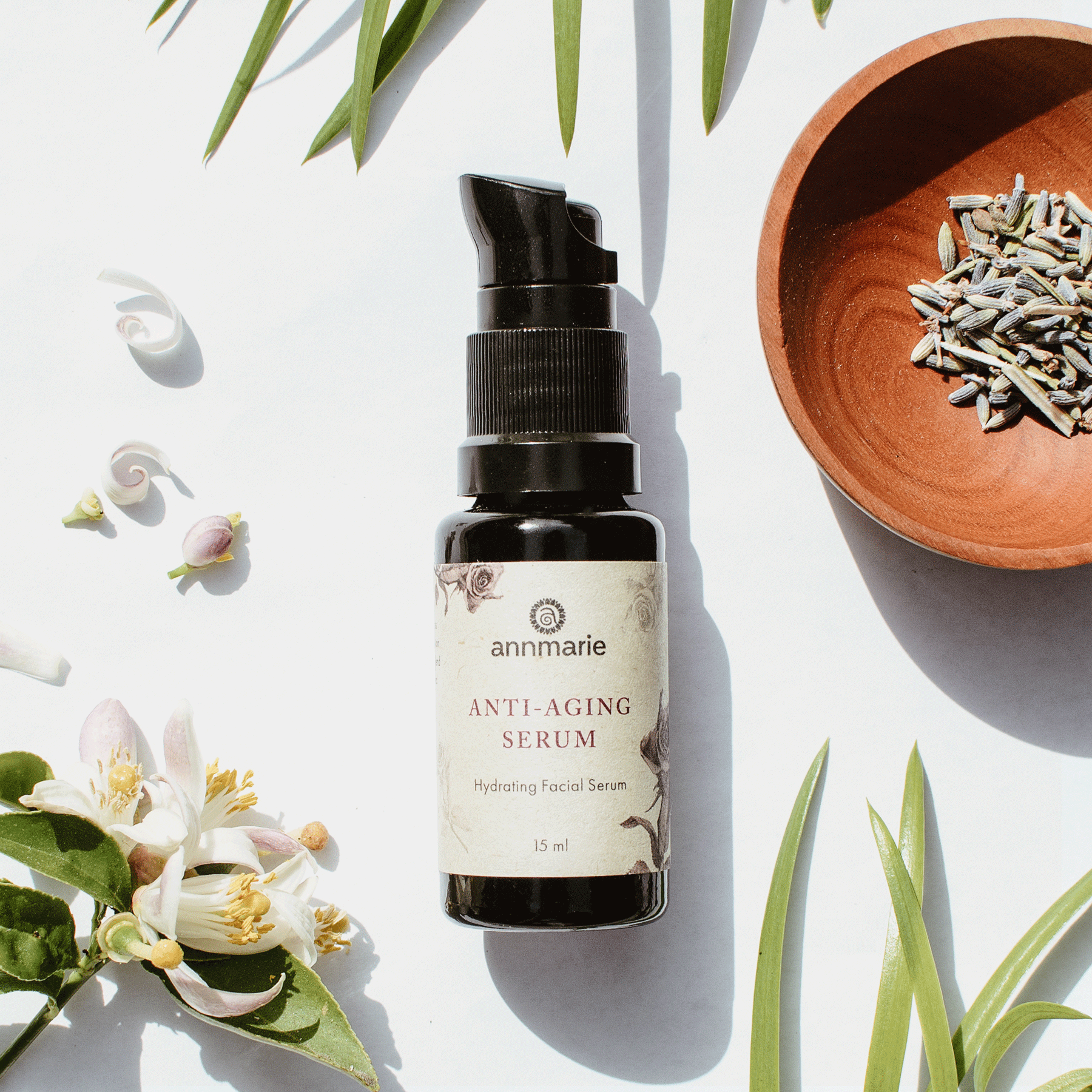 Annmarie Skin Care Anti-Aging Serum hydrating facial serum 15 ml pump bottle with botanical packaging displayed with greenery for natural skincare product styling.
