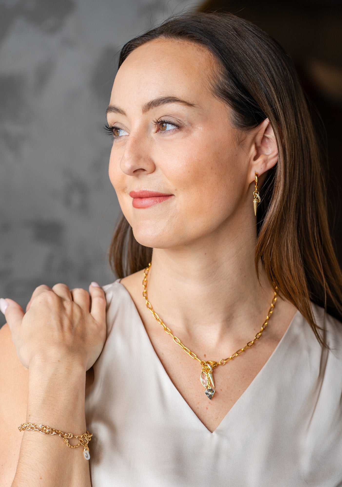 Gold necklace with marquise crystal, spike charm, and smoky gem drop on a textured clasp