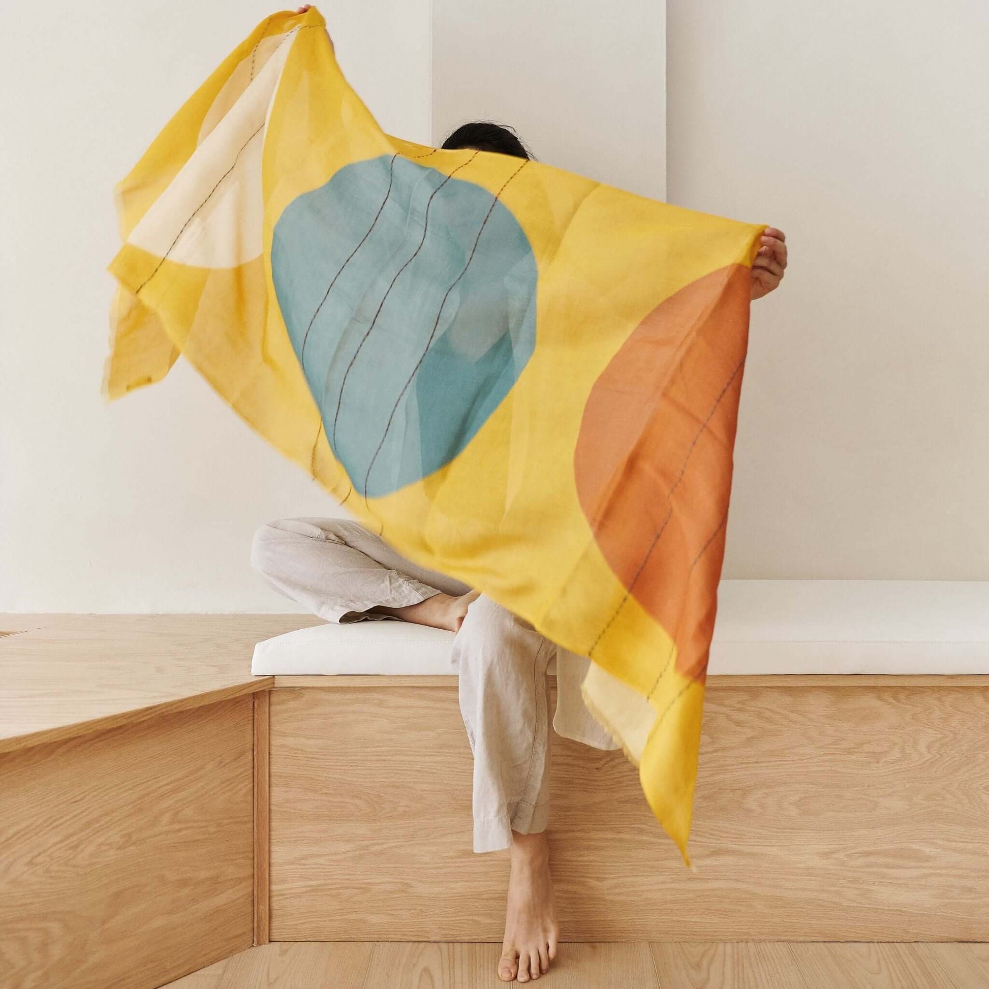 Cirq Sun Yellow Green Circle Pattern Hand Embroidered  Linen Silk Handloom Scarf displayed by a person sitting on wooden steps.