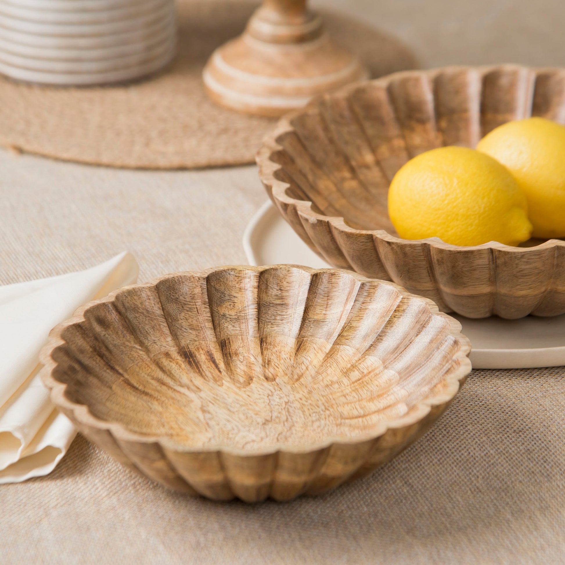 Scalloped wooden bowls styled with fruits on a dining table