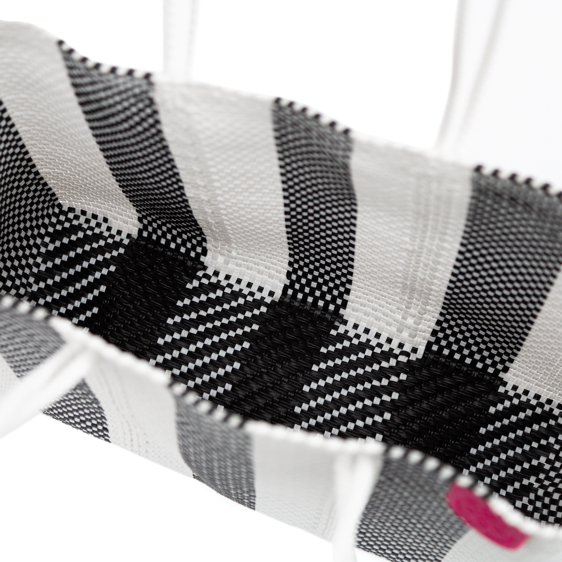 Inside look of Zebra super tote, A black and white striped oversized tote bag with a purple pompom decoration, and a shoulder strap.