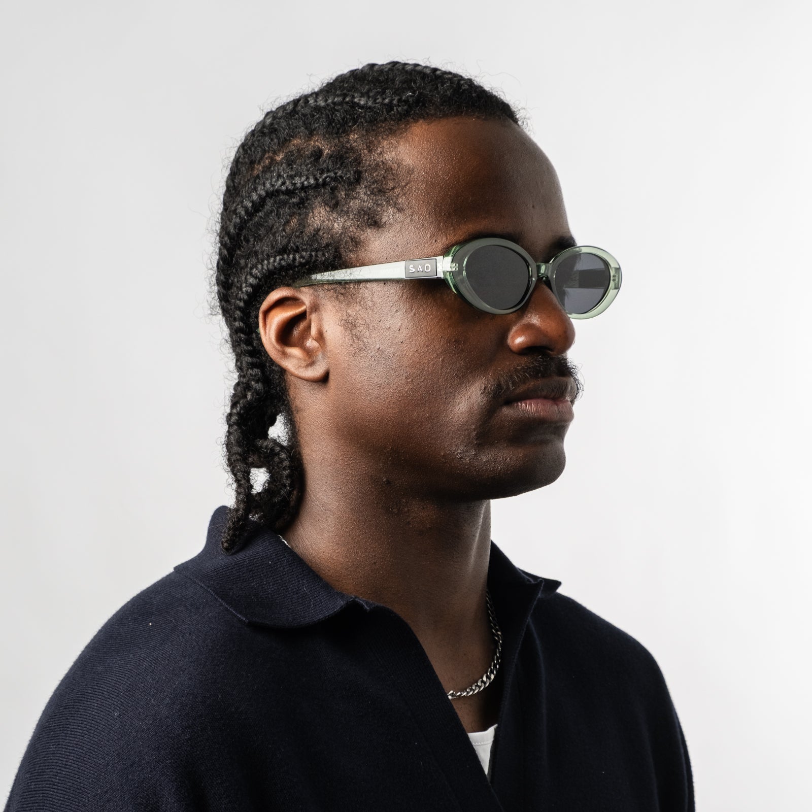 Male wearing Sad Eyewear Bloom oval sunglasses in sea glass green with tinted black lenses